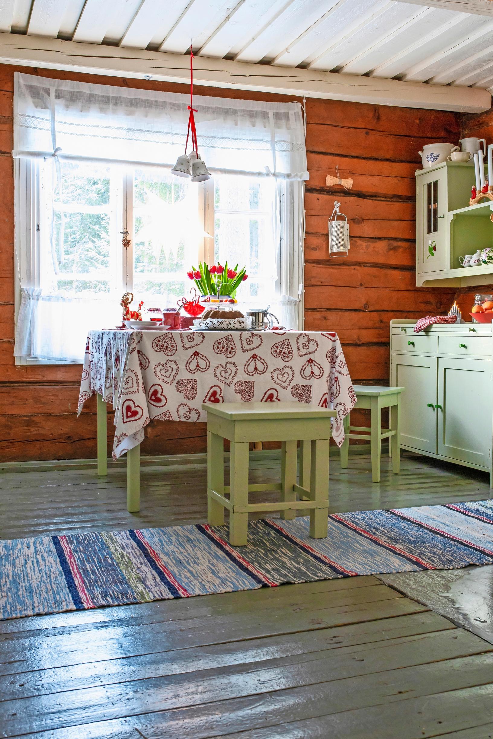 A red-and-white tablecloth paired with green-painted kitchen cabinets.