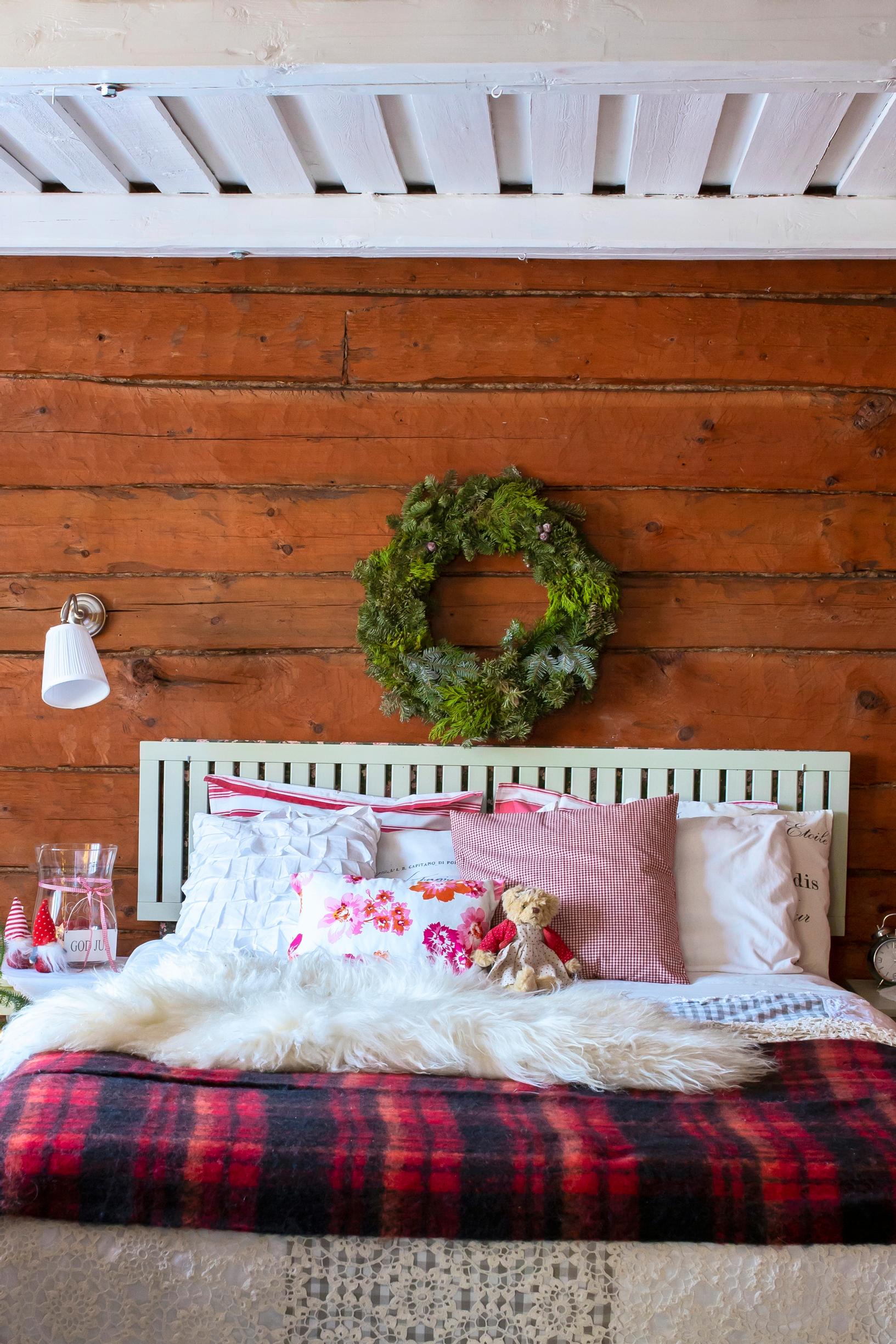 A wreath of evergreen branches decorates the log wall in the sleeping area