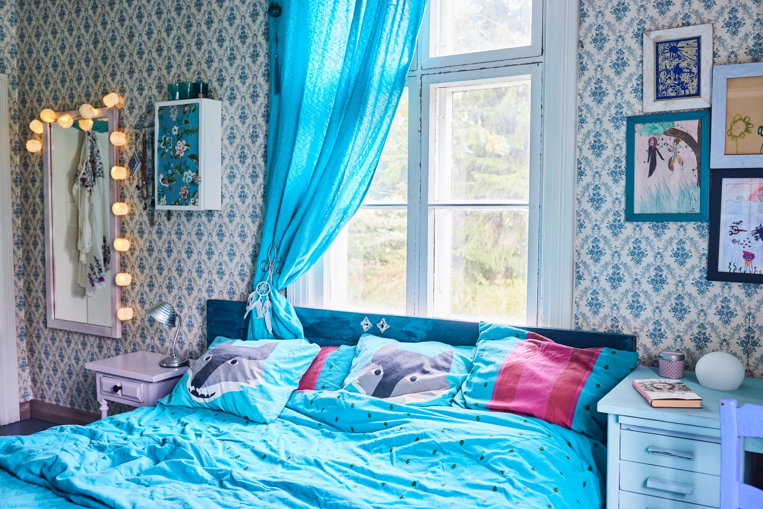 Bedroom with turquoise textiles and wallpaper