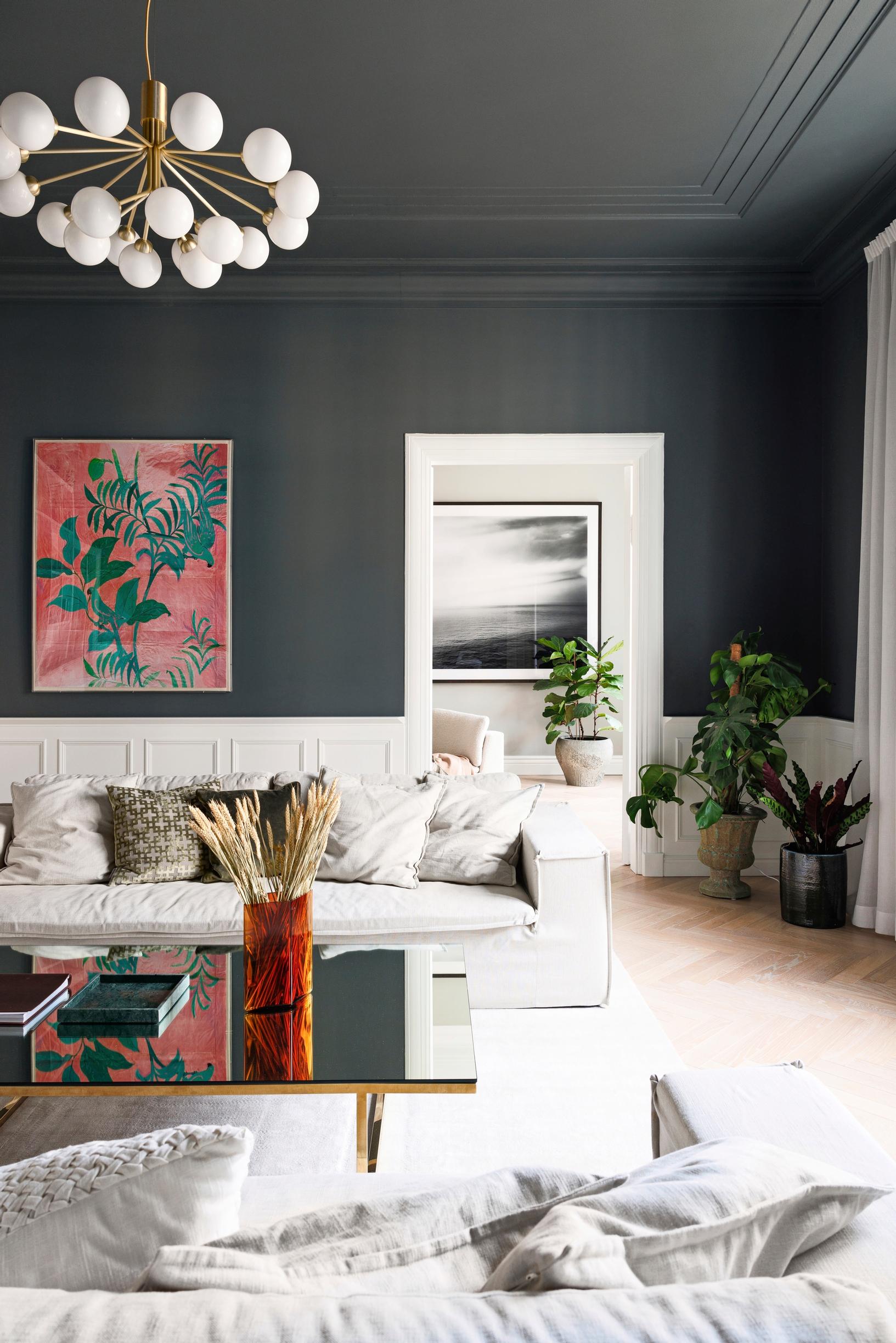 A light sofa in the living room, dark walls, and light wall paneling.