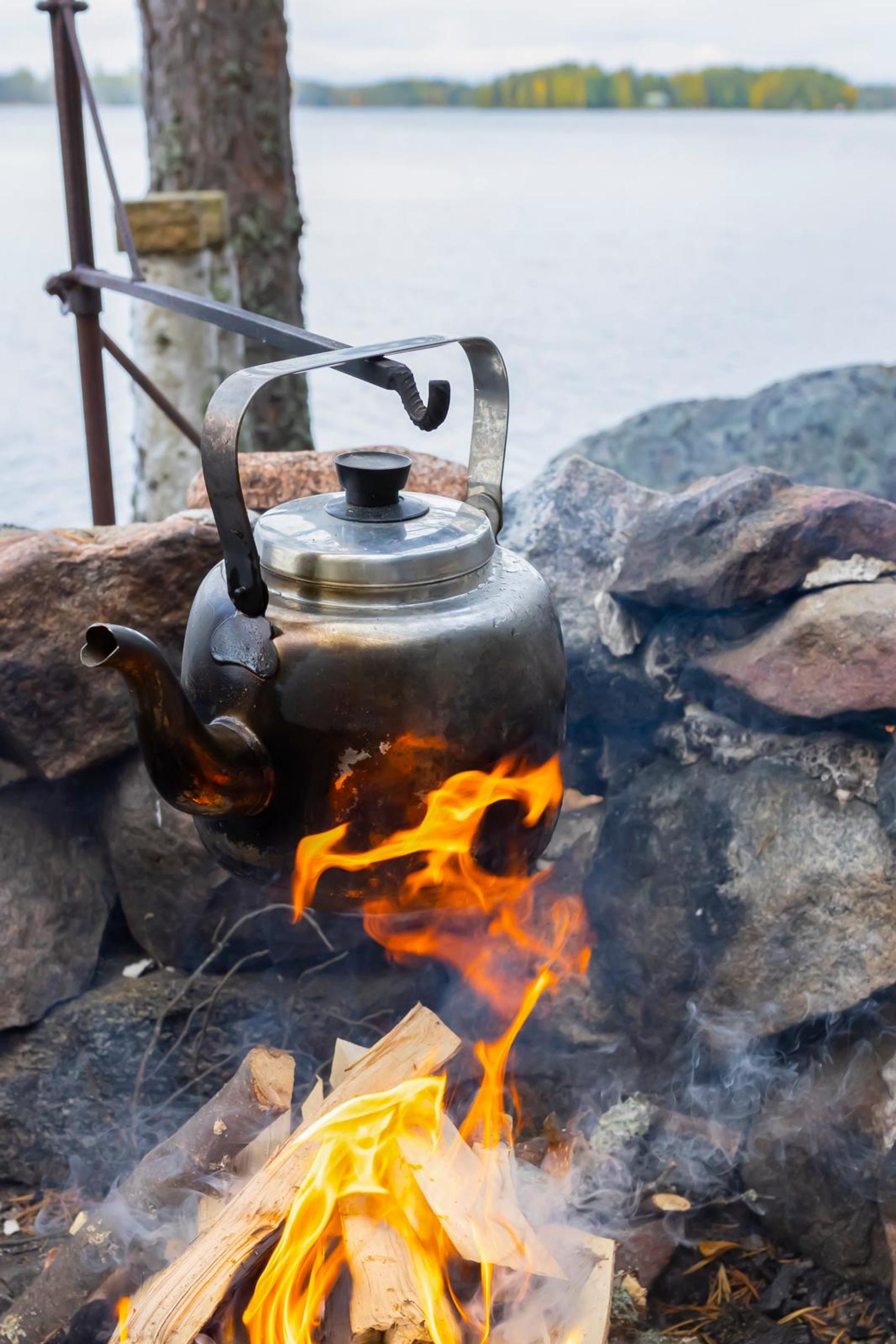 A soot-blackened coffee pot on the fire by Lake Saimaa