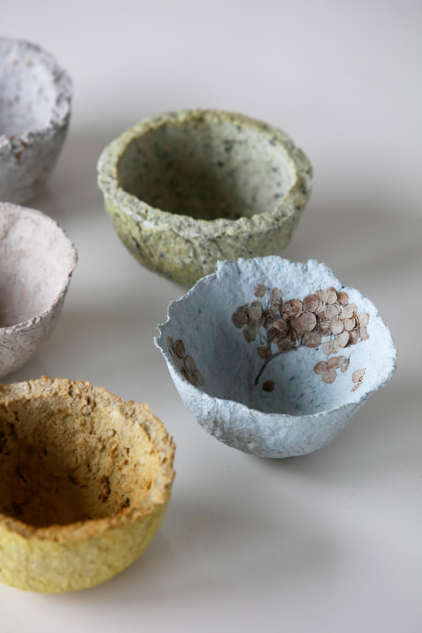The bowls have a rustic feel, with seed pods mixed into the papier-mâché and dried flowers pressed onto the surface.