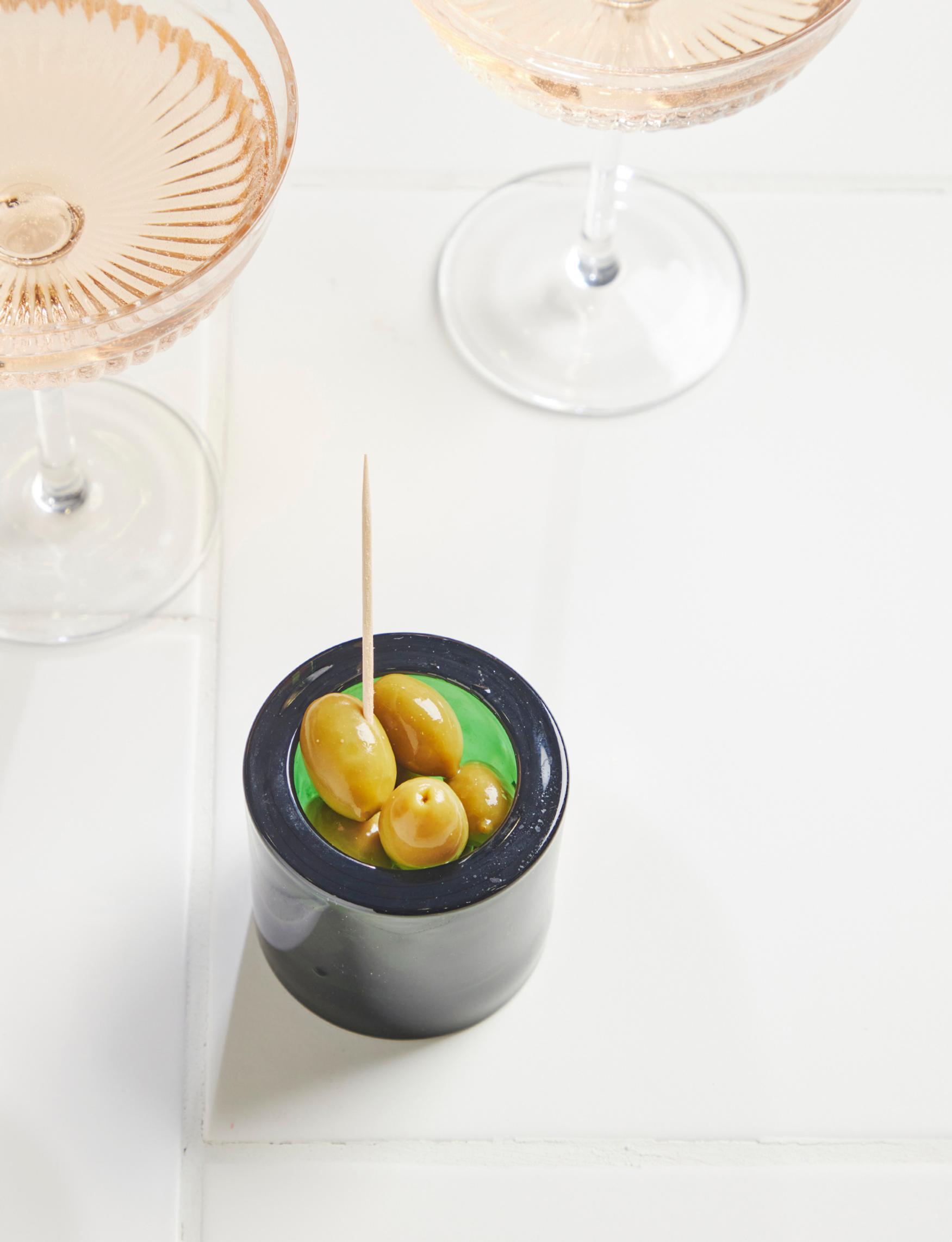 A Kivi tea light holder filled with olives.