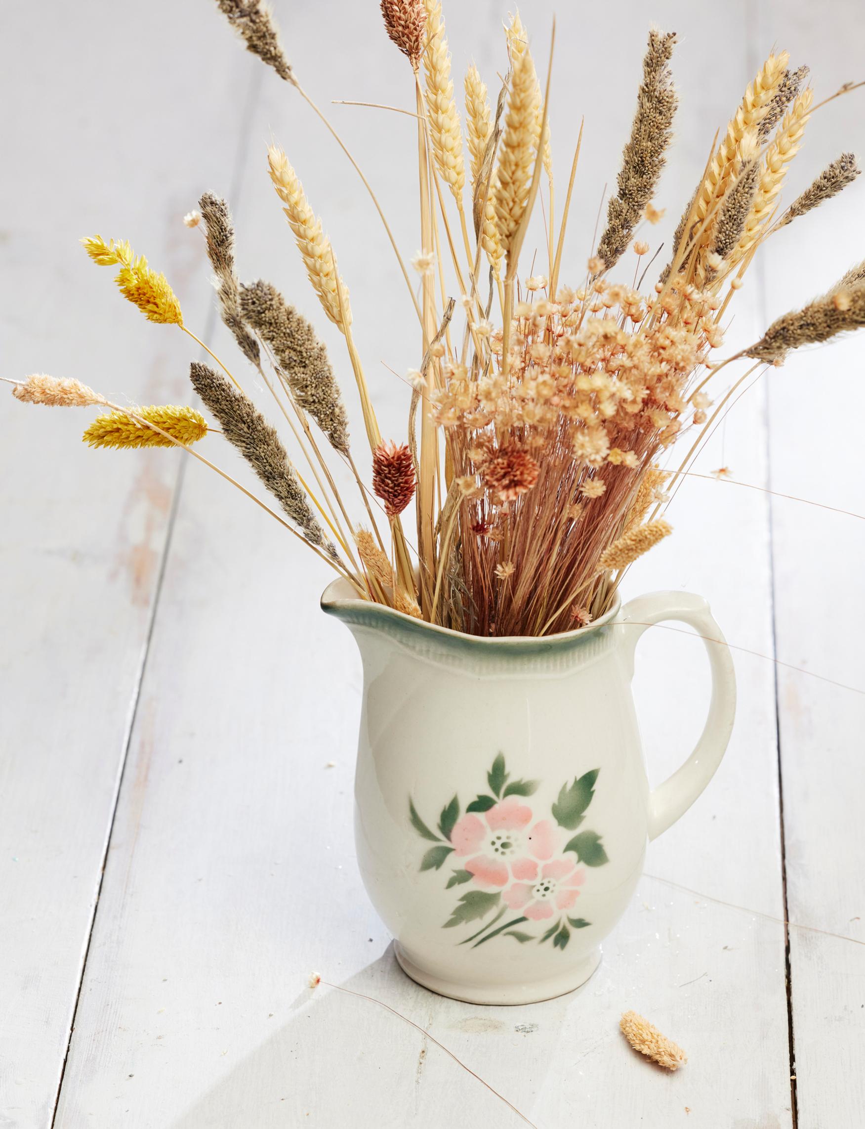An old Arabia milk pitcher holding dried flowers.