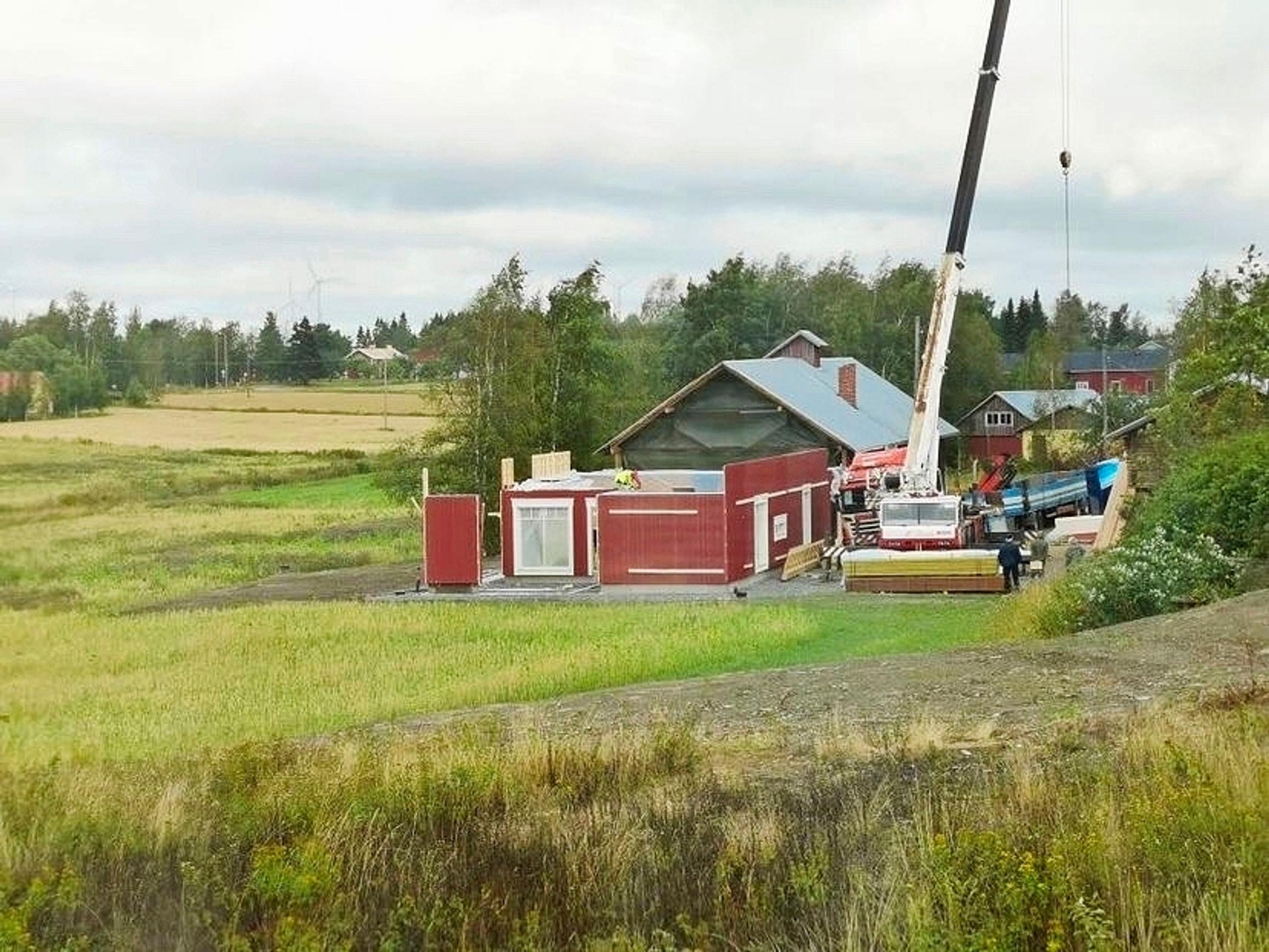 A new house being built in place of the old barn. Prefabricated elements are being lifted by a crane.