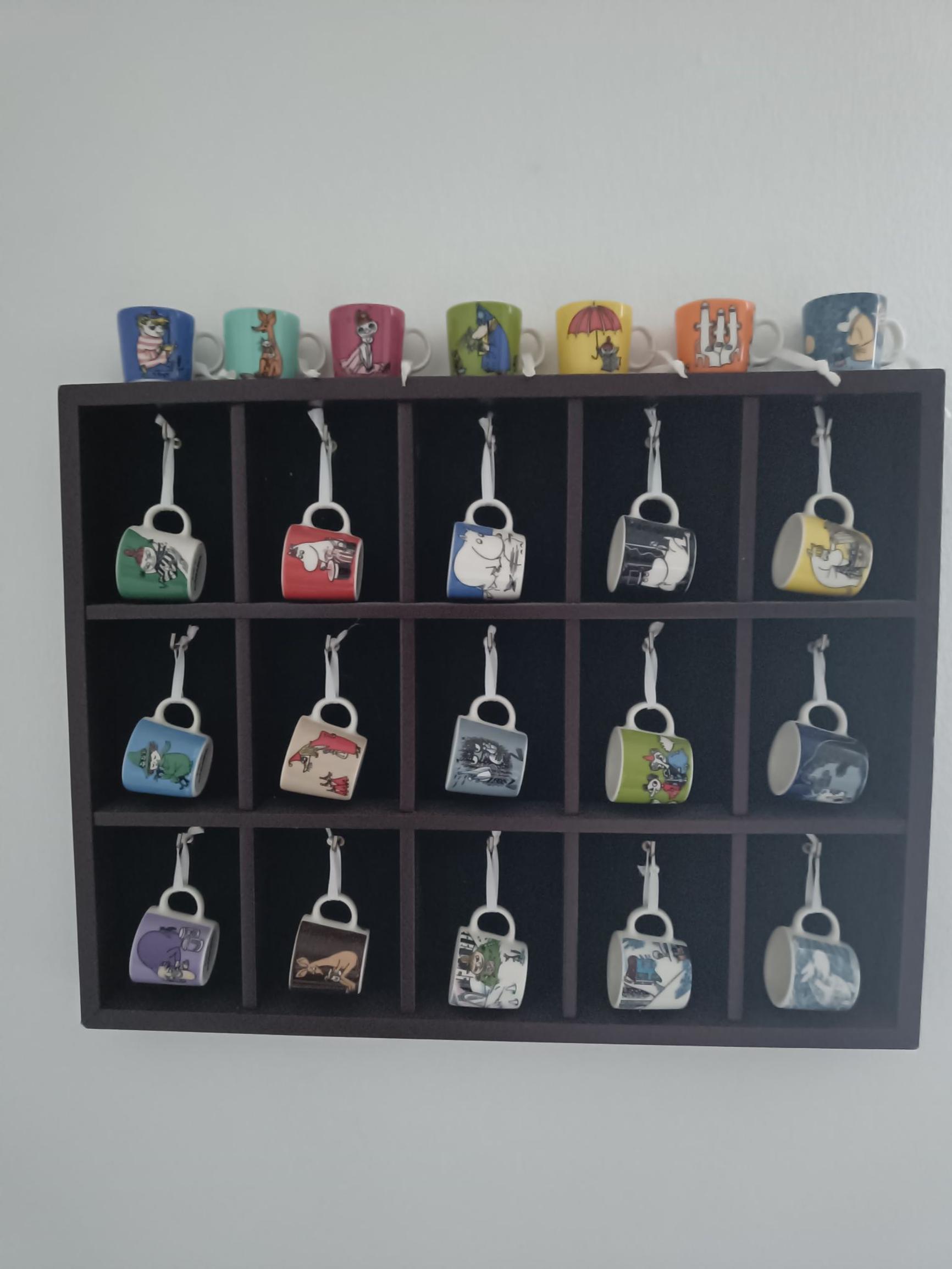 22 mini Moomin mugs hanging on a shelf
