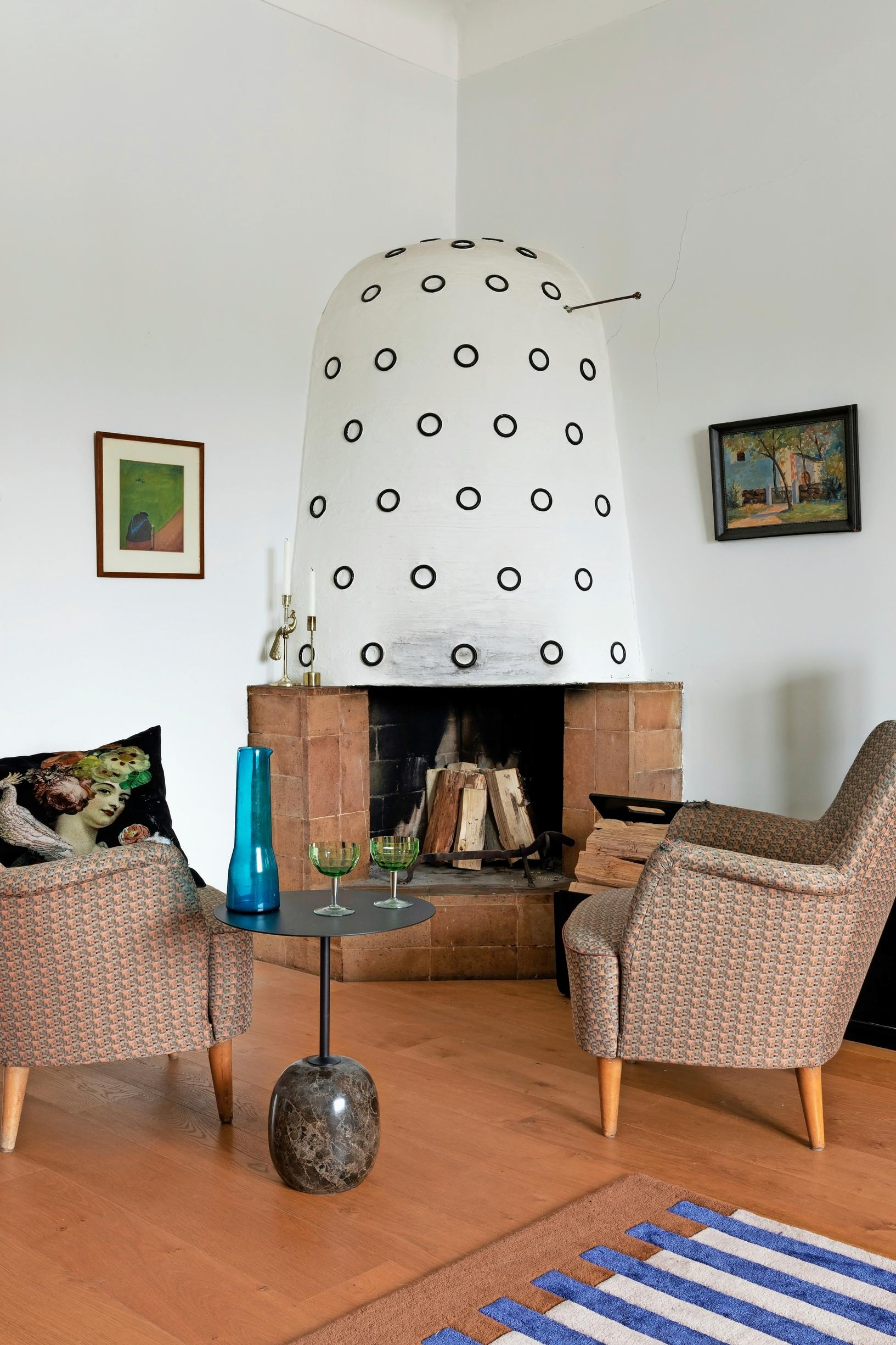 Living room with an open fireplace in the corner and armchairs beside it.