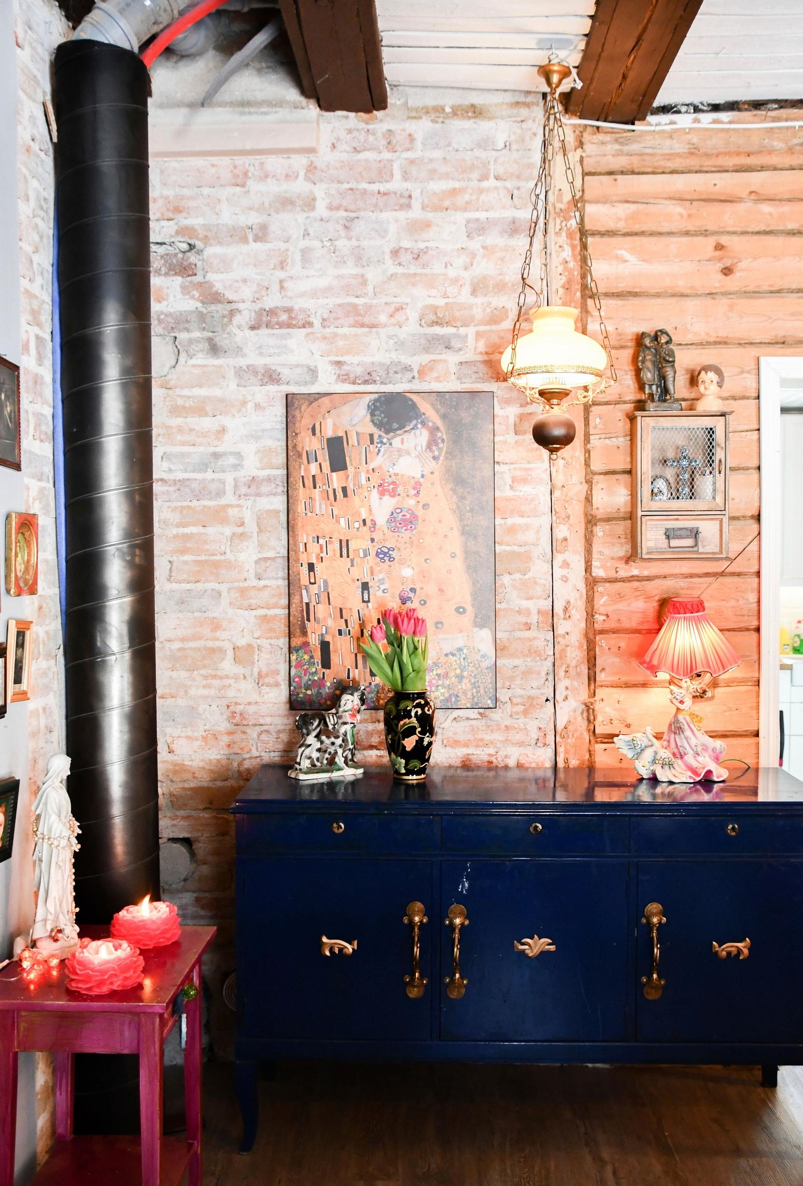 A blue dresser against a rough brick wall.