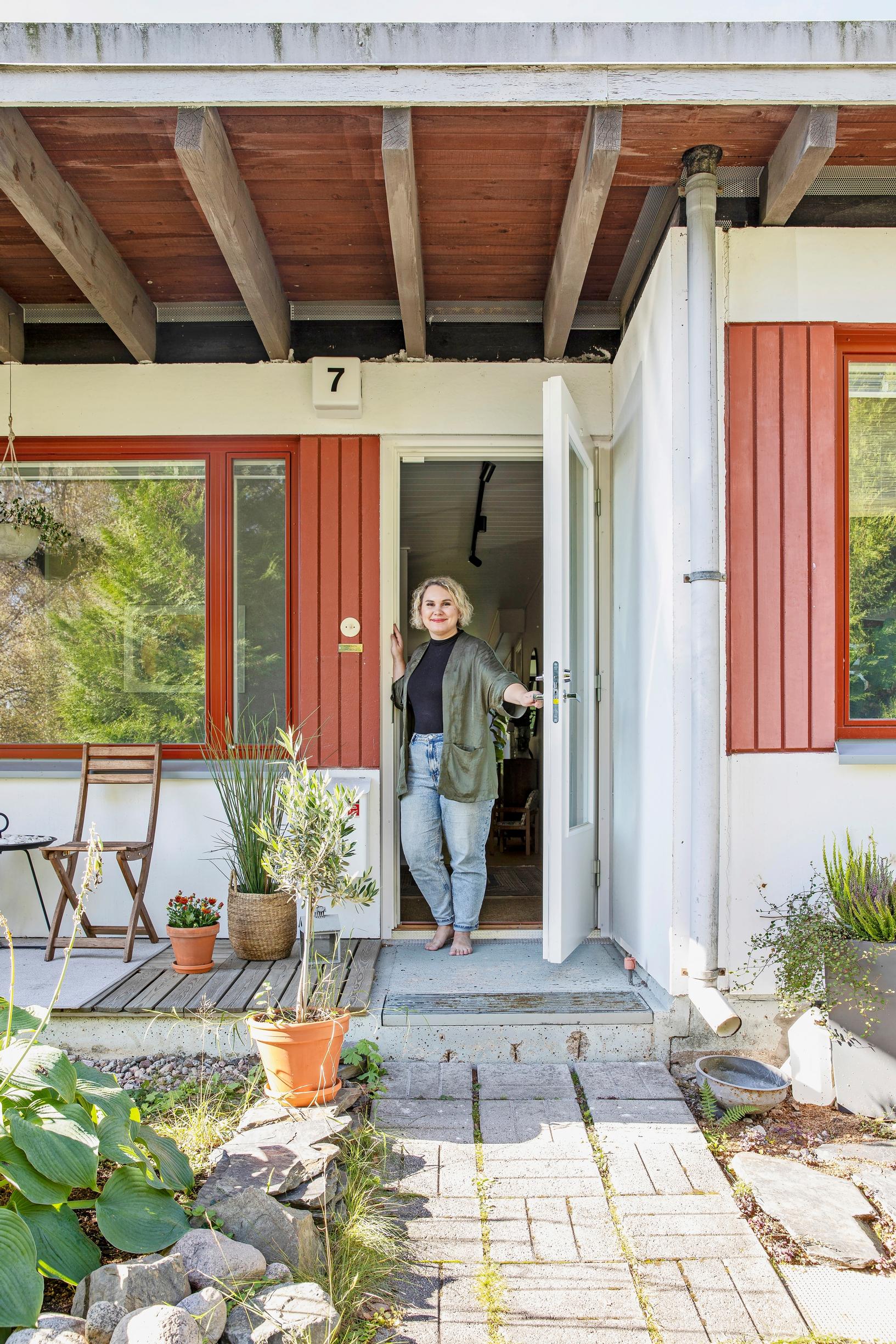 Photo of a woman standing at the doorway of a 1960s row house.
