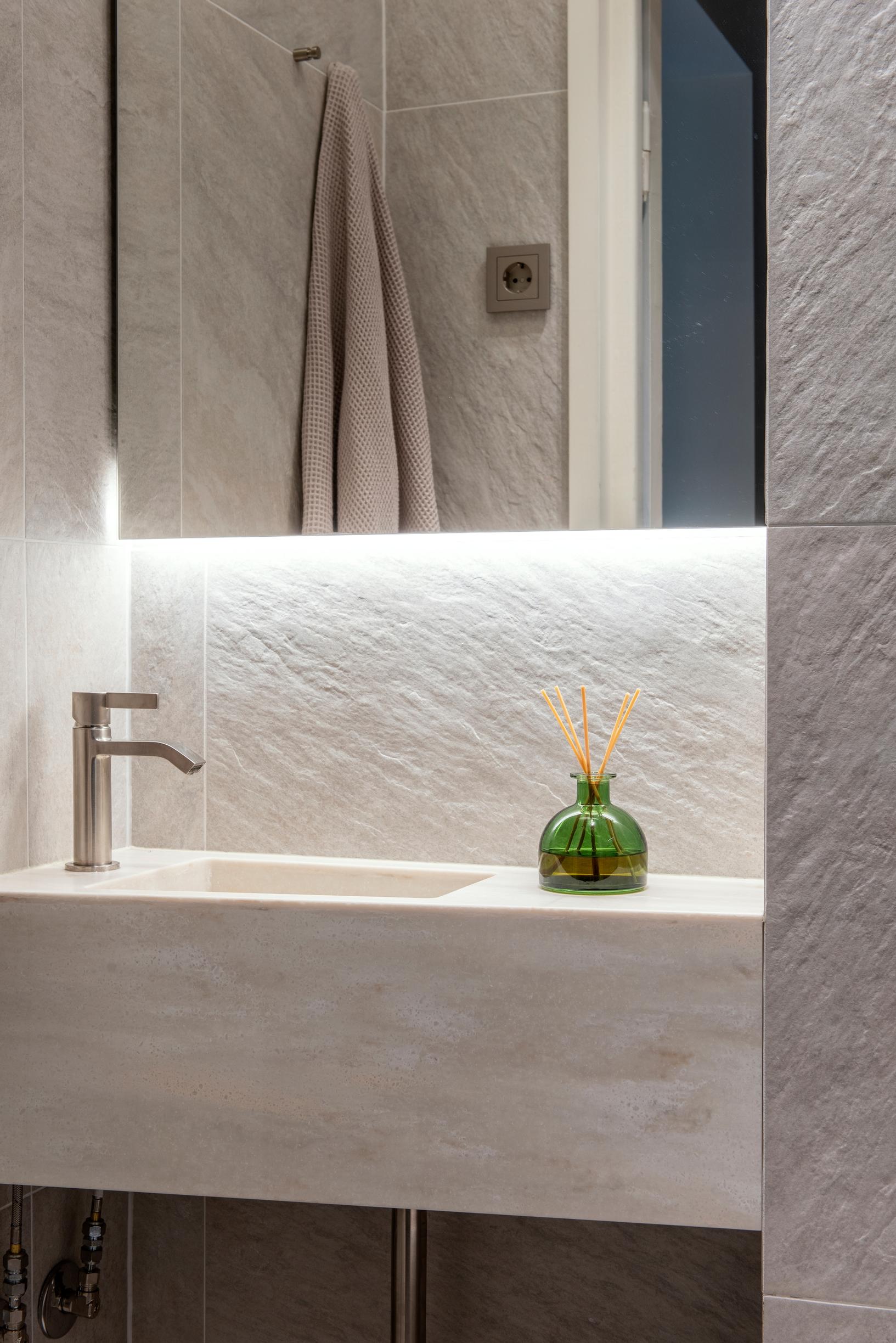 A small restroom tiled in a light shade
