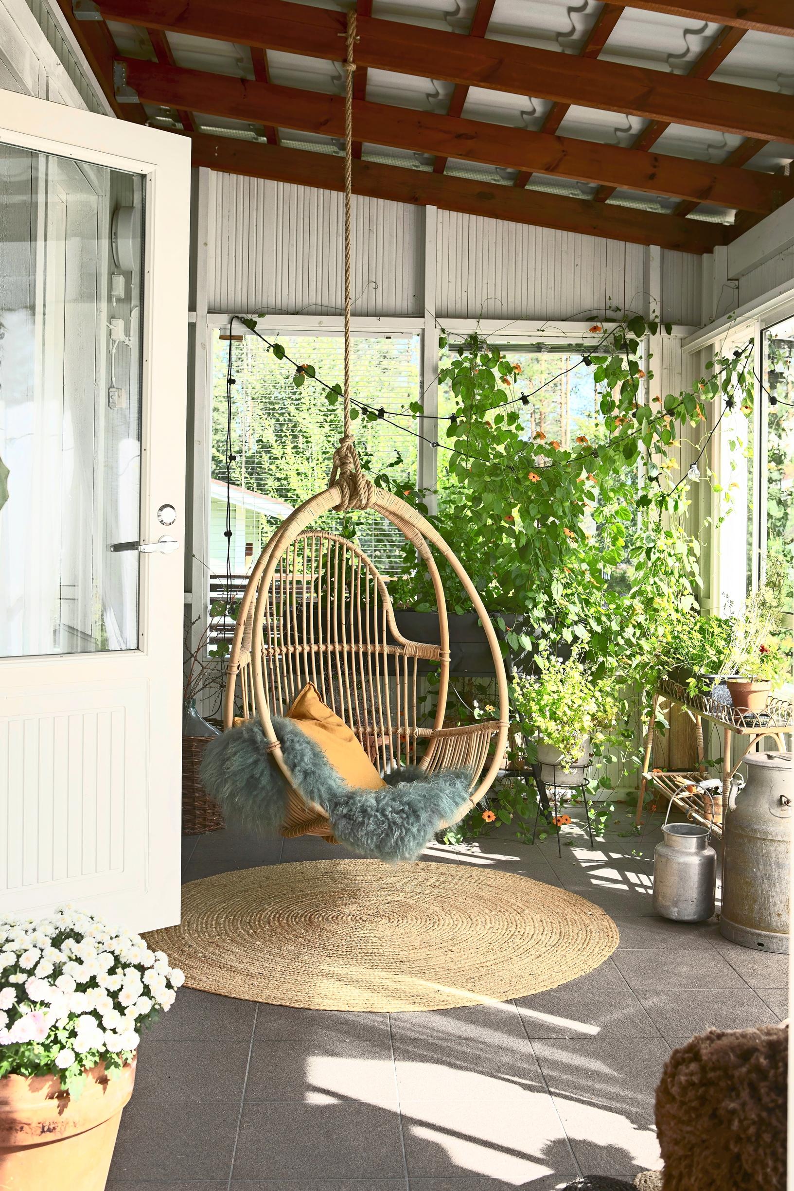 A Parolan Rottinki hanging chair in the single-family home's greenhouse