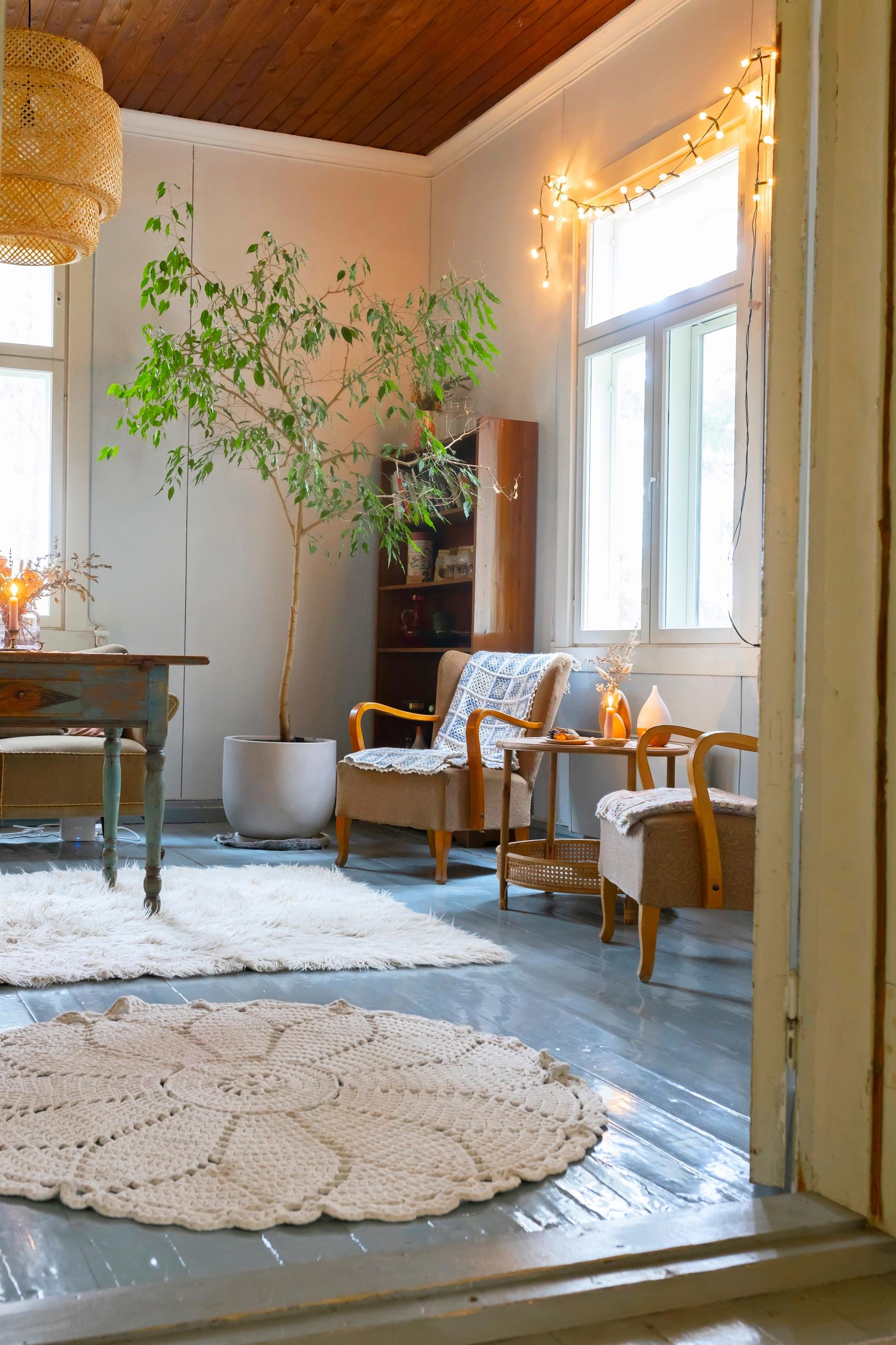 Wooden floor, old armchairs, and white rugs.