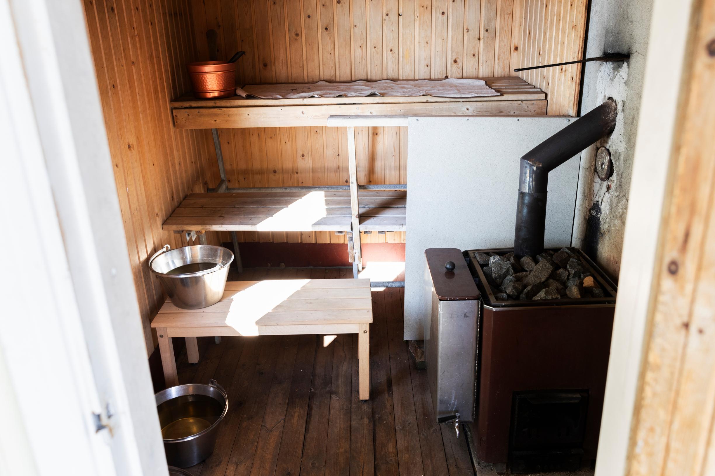 Sauna benches, stove, and buckets, sunlight streaming in