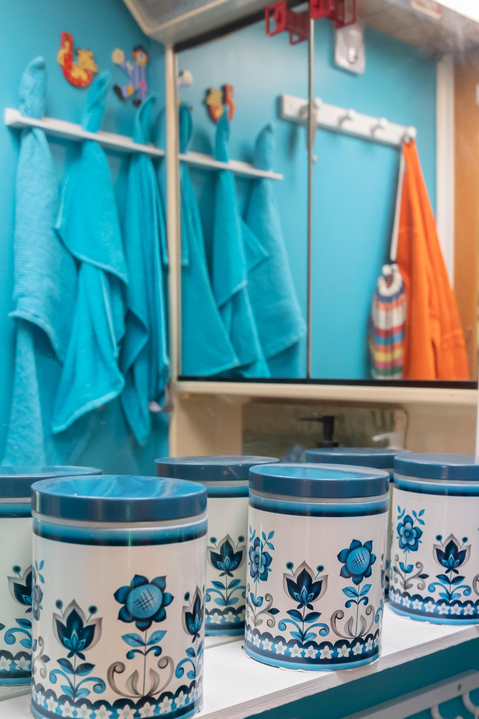 blue-and-white containers on a shelf; the mirror reflects turquoise and an orange towel