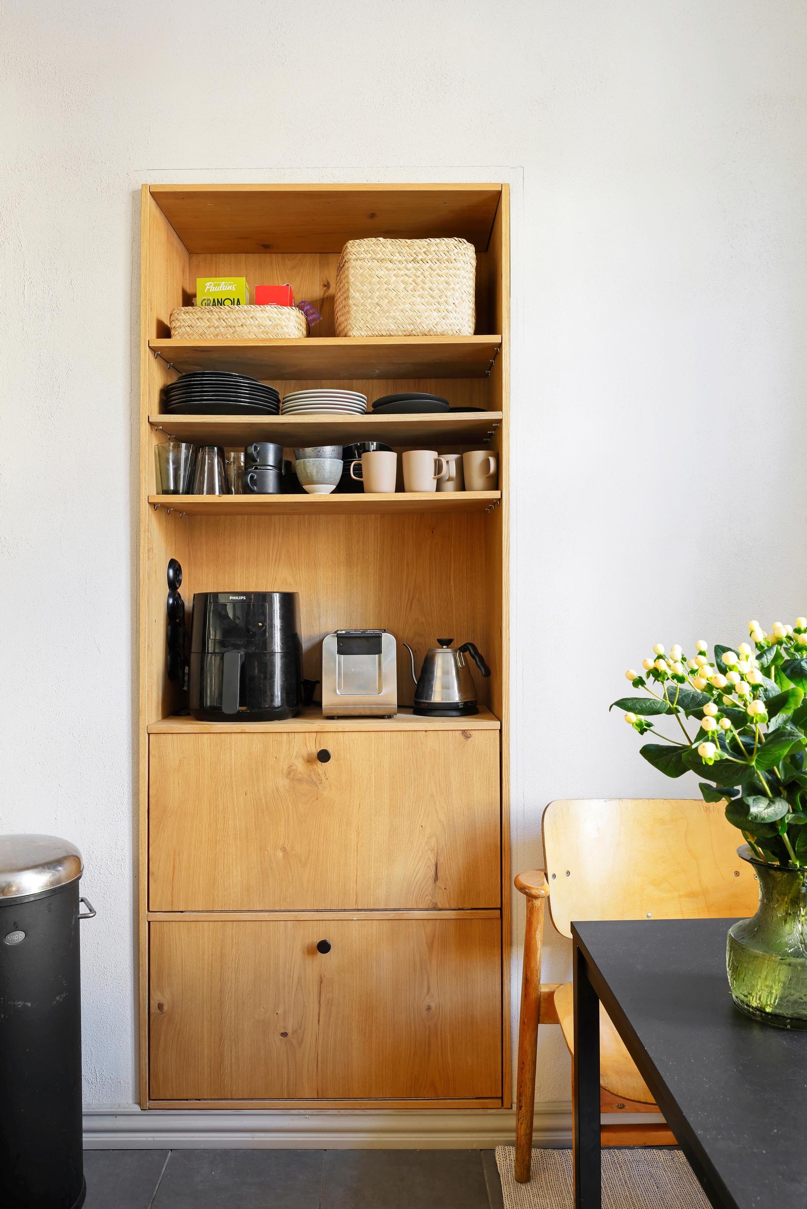 A wooden storage unit built into the doorway features four open shelves on top and two cabinets at the bottom.