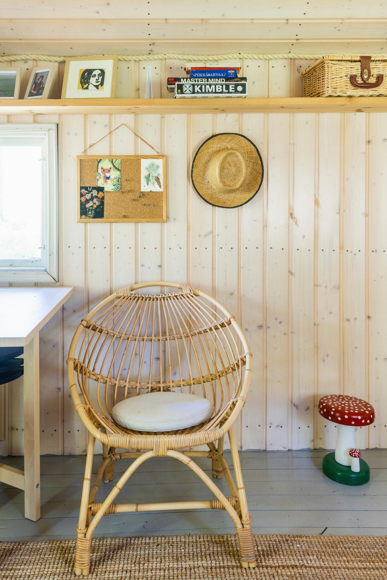 a wicker chair, a mushroom stool, plus a shelf and items on the wall