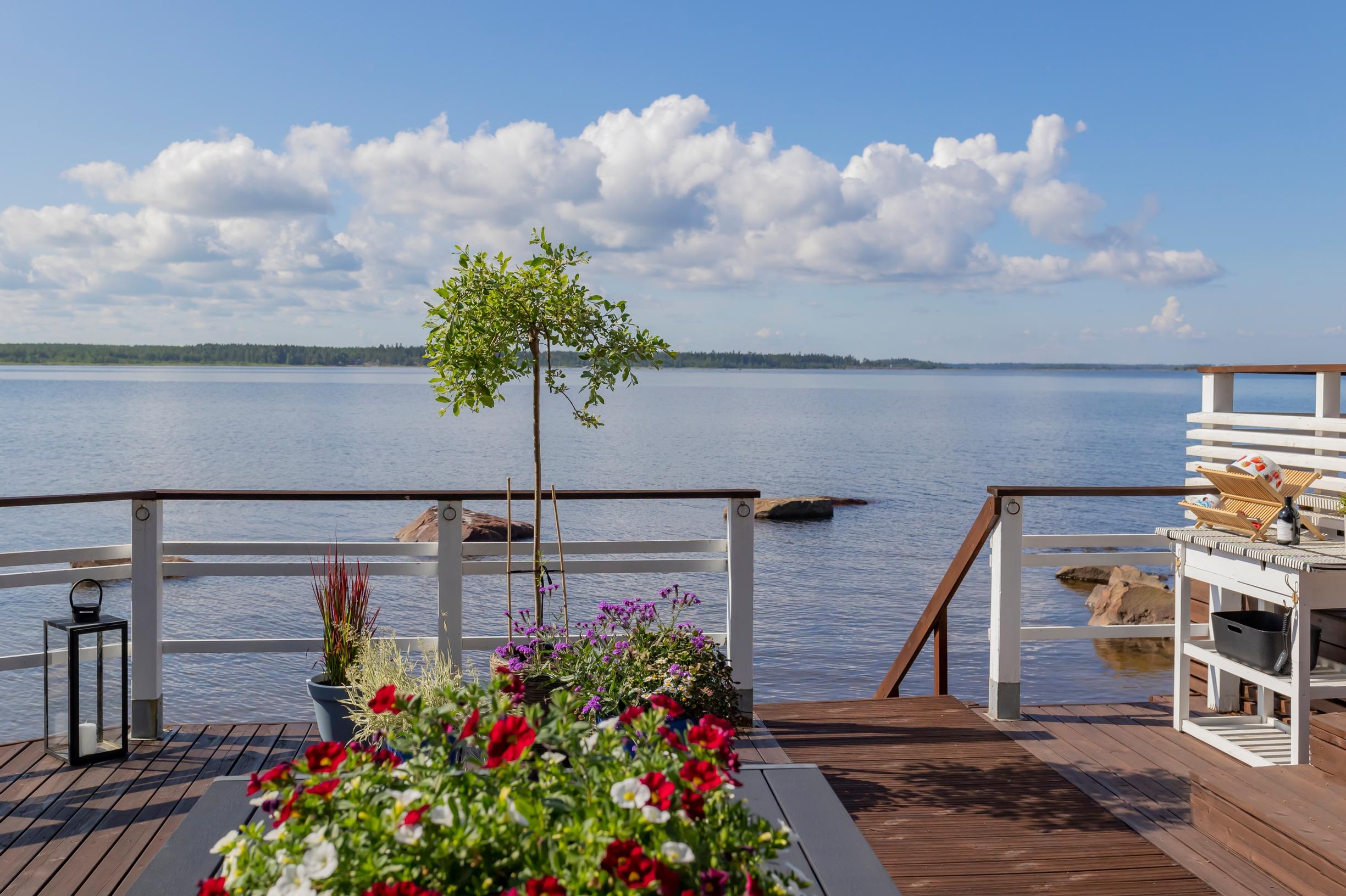 summer flowers, a lantern, and a side table on the terrace, with steps leading down to the sea