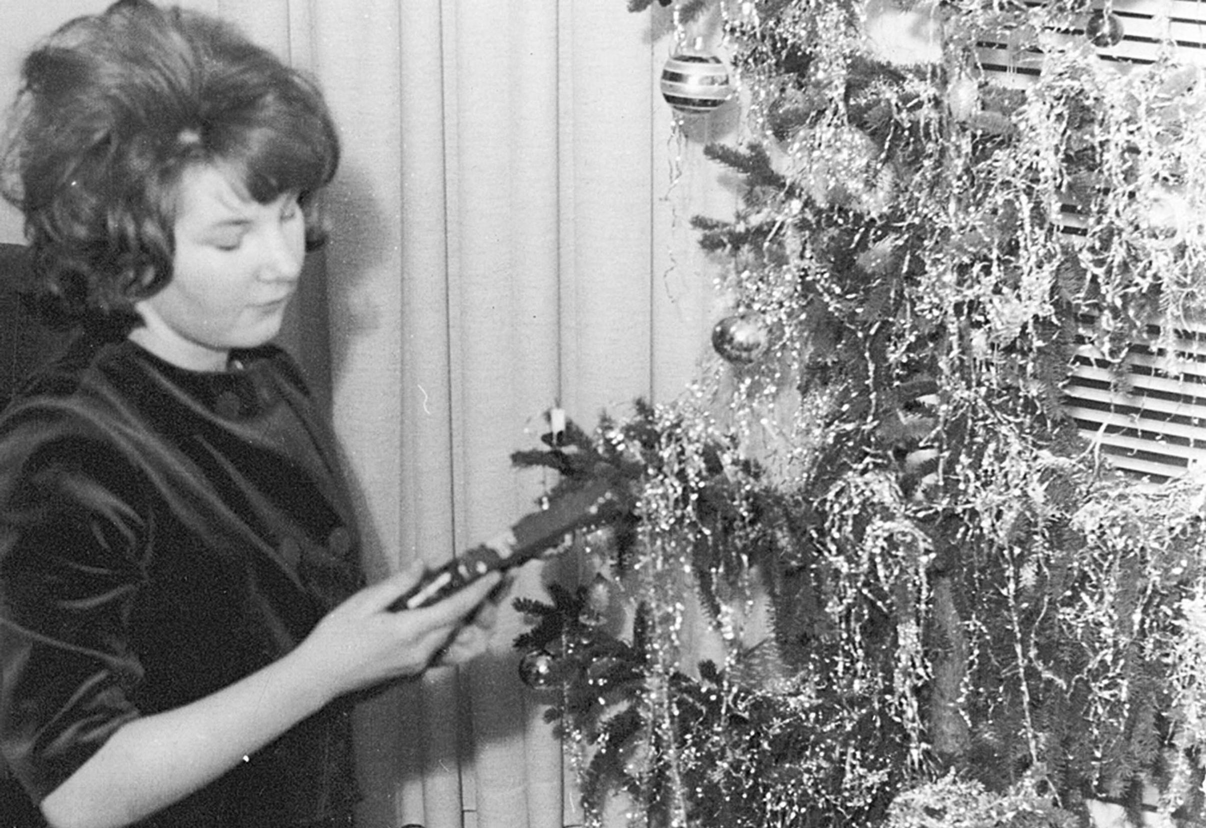 Black-and-white photo of decorating a Christmas tree