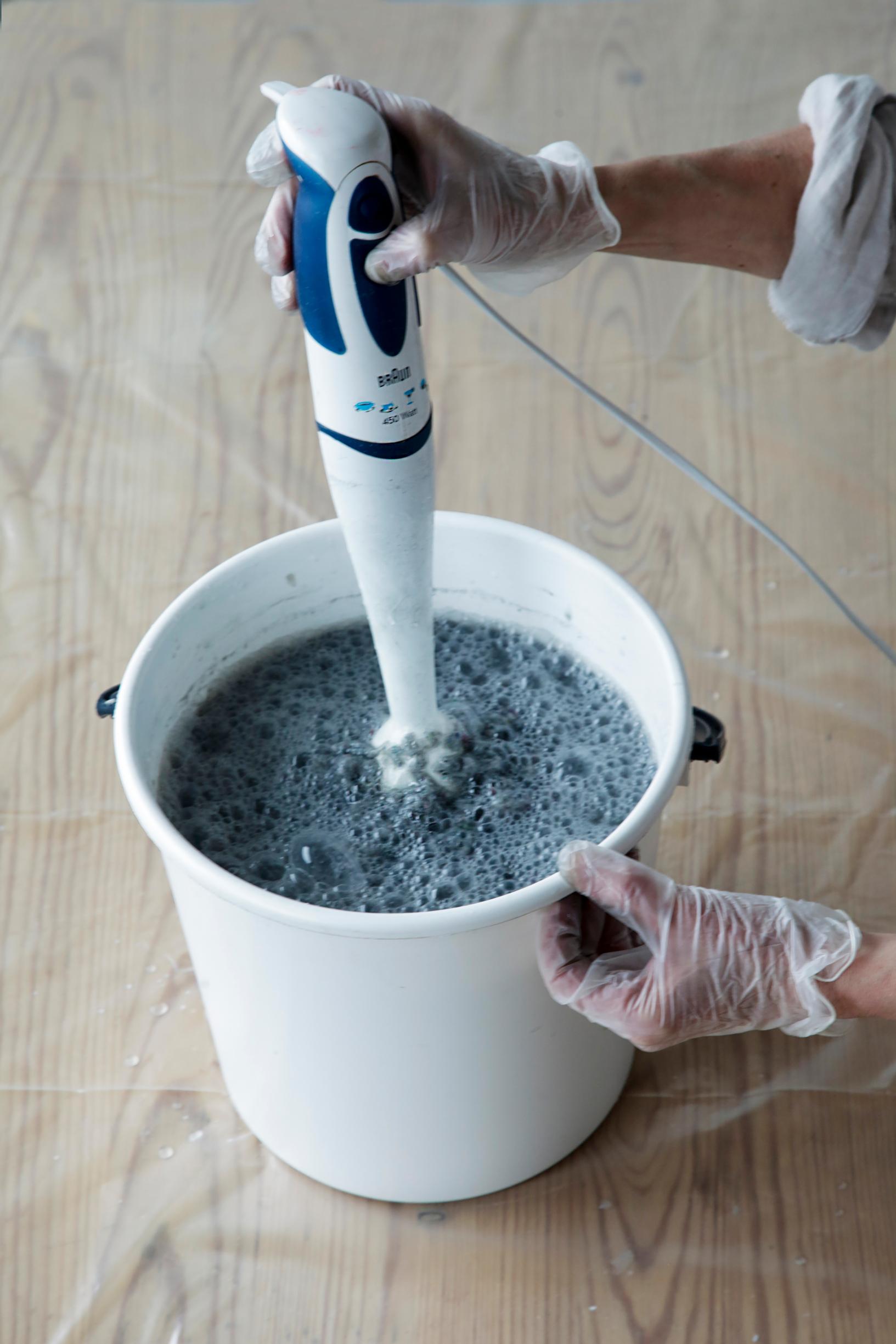 The papier-mâché is blended in a bucket with a hand blender.