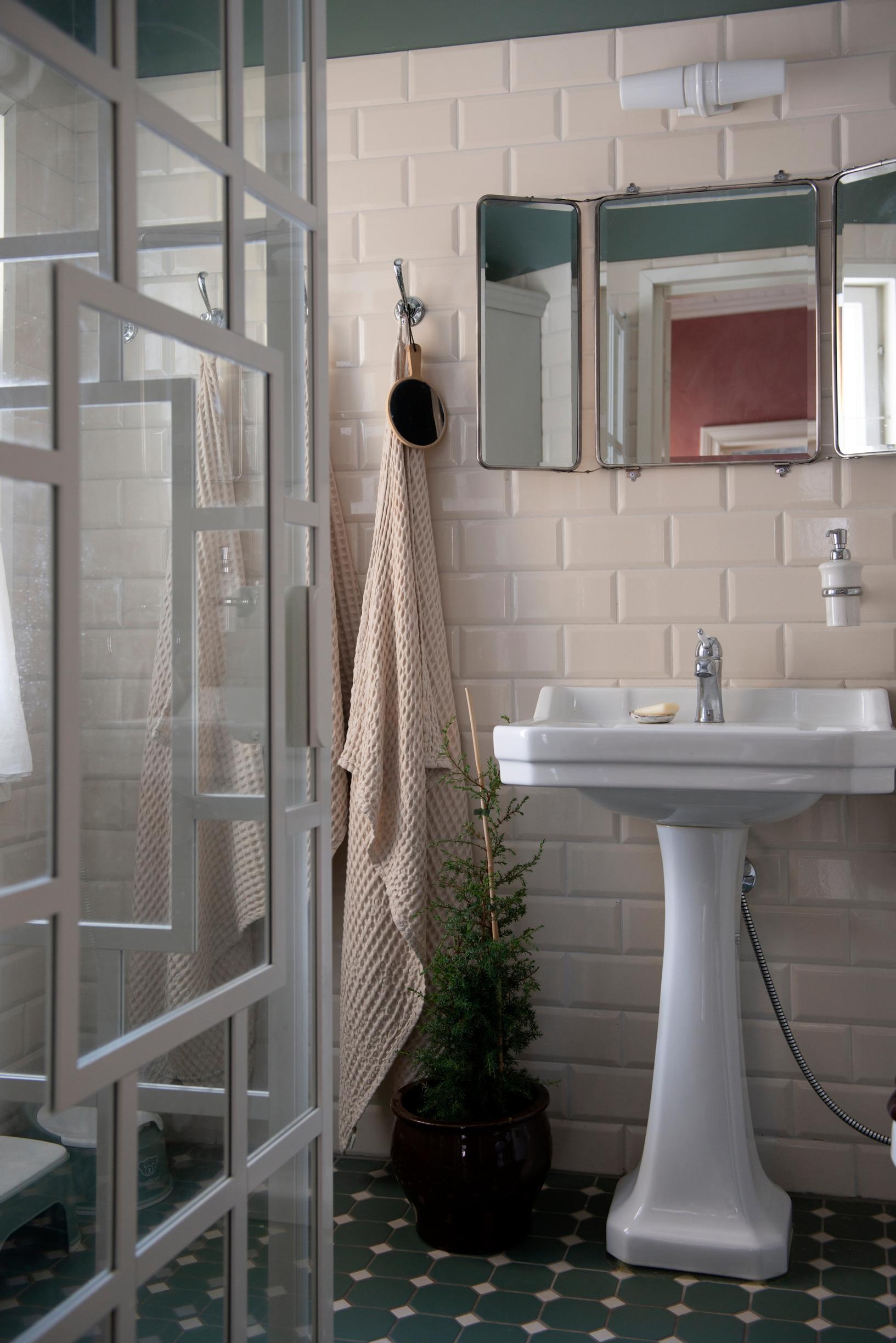 Bathroom with powder-colored tiling, white sink, and green-hued floor tiles.
