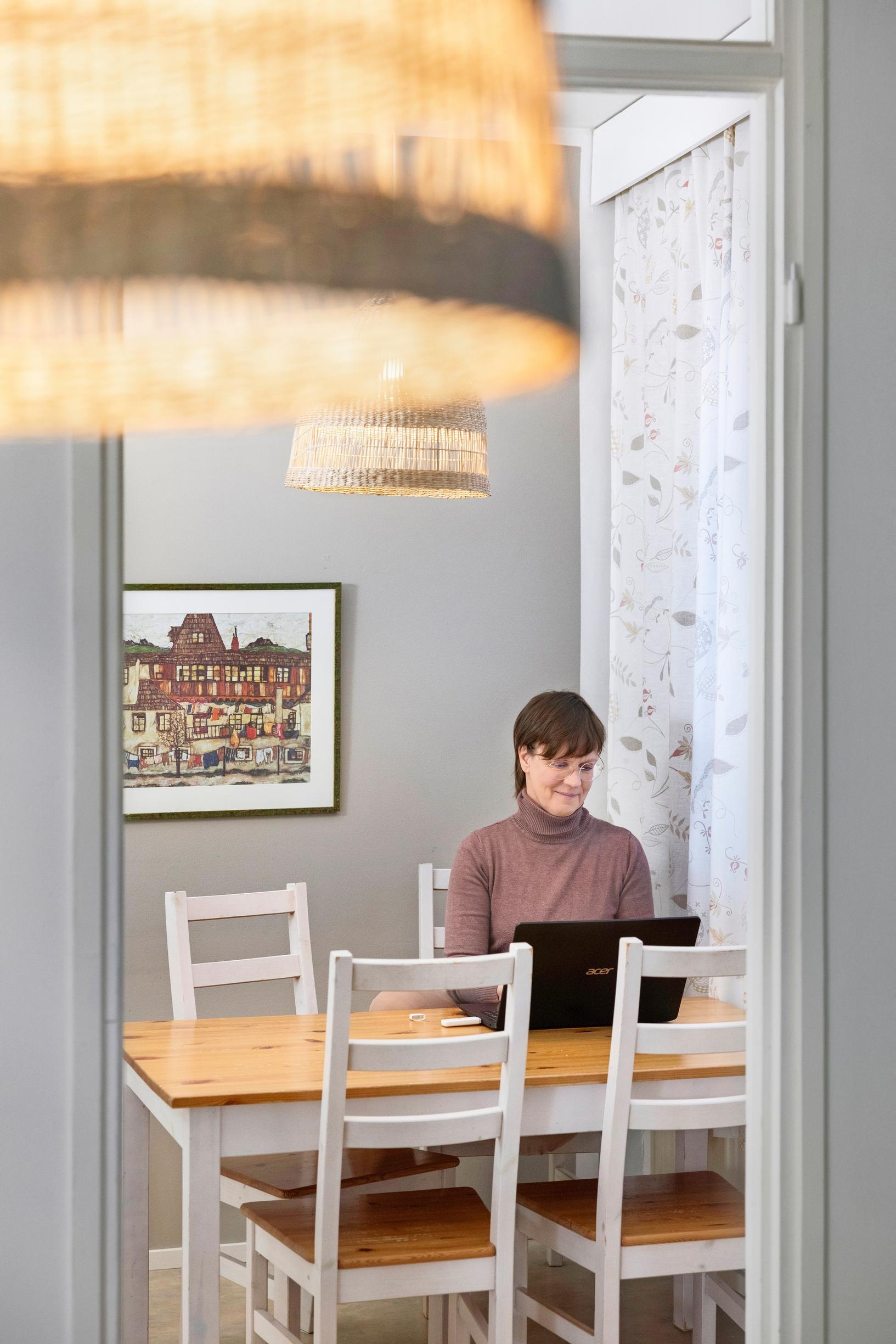 a woman sitting at the dining table with a laptop