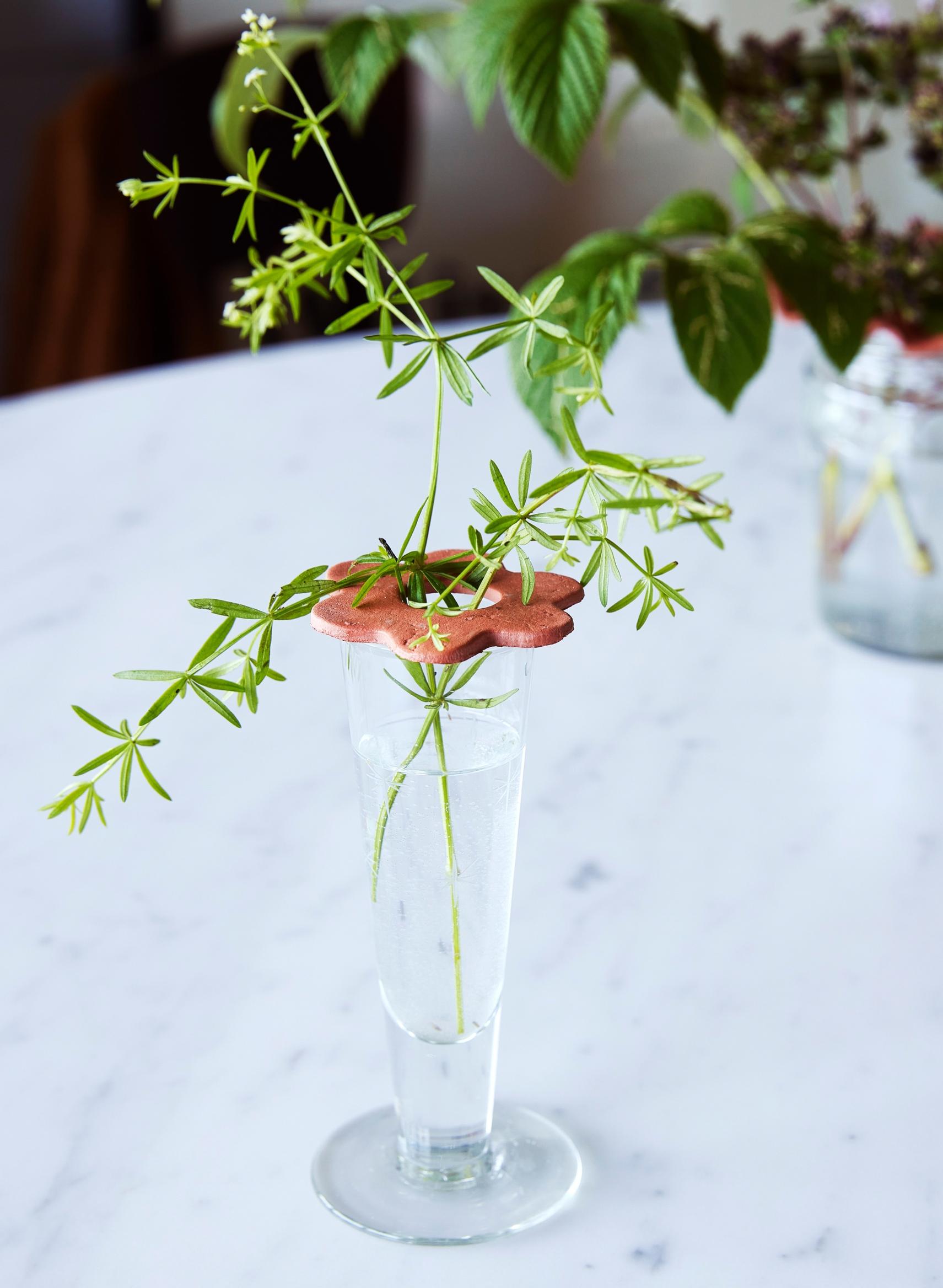 A small vase with a flower support made from air-dry clay.