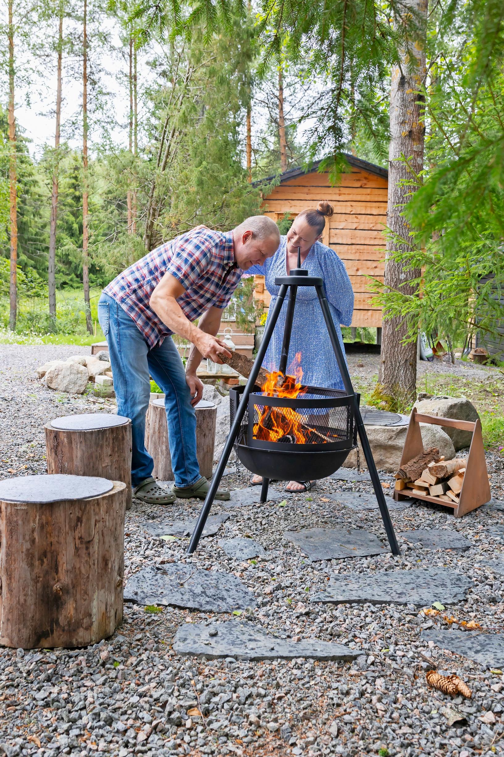 Jutta and Pasi Taavitsainen by the fire pit in the yard of their sauna cabin in Sipoo