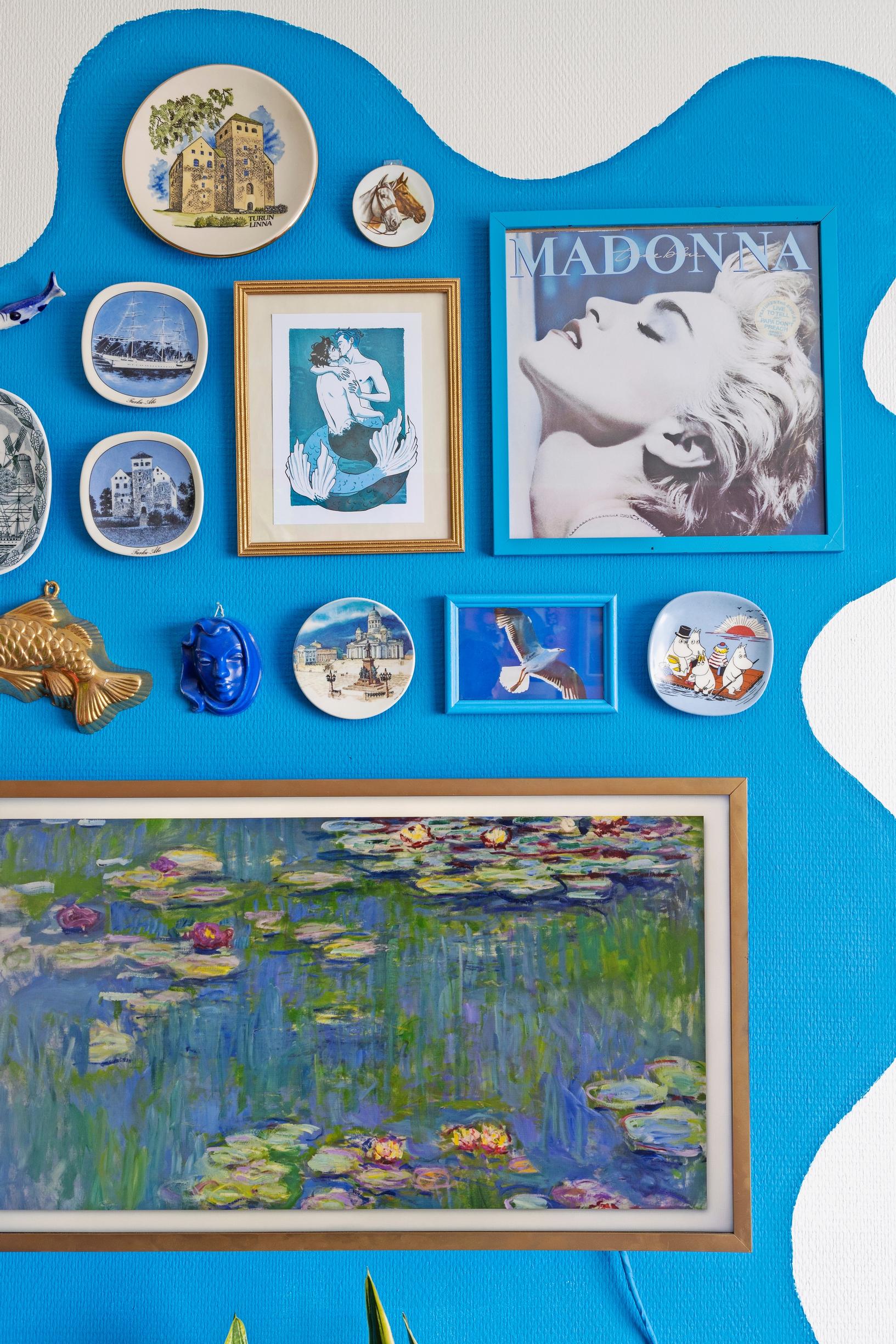 A collage of paintings on a blue-painted wall.