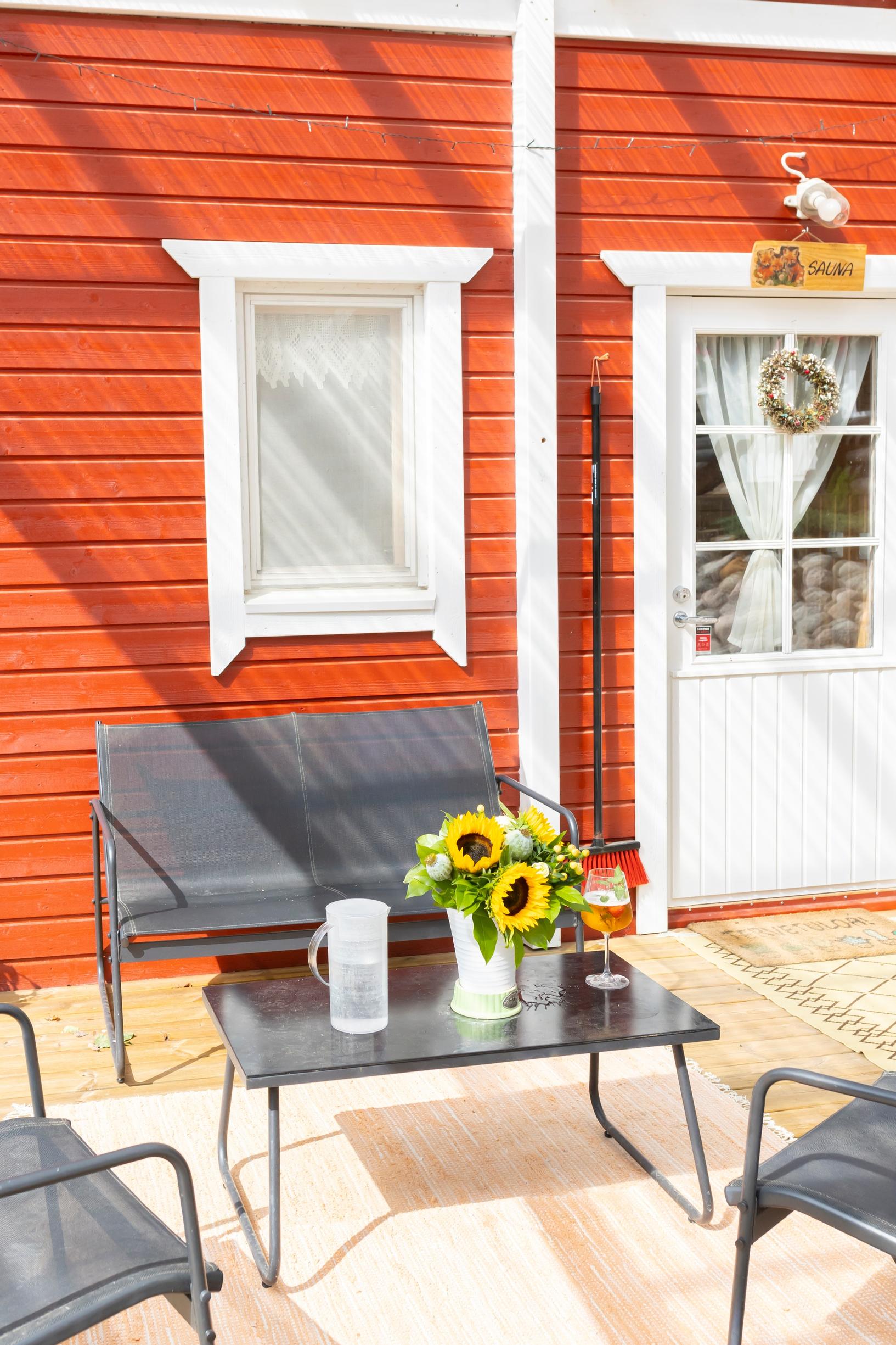 Dark garden furniture set on the terrace in front of the red house, sunflowers on the table