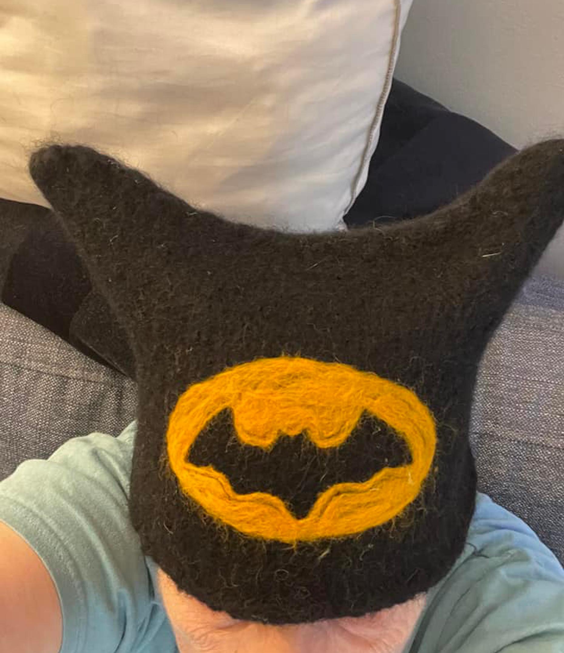 A woman wearing a felted hat with a Batman design.