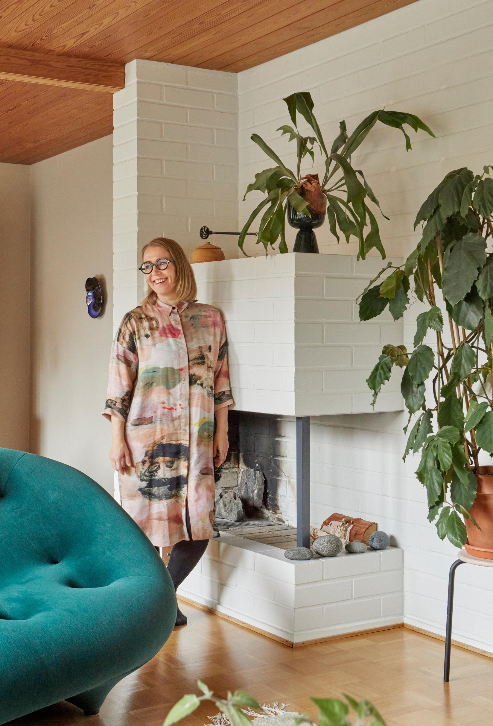 Maija in the living room with an open fireplace.