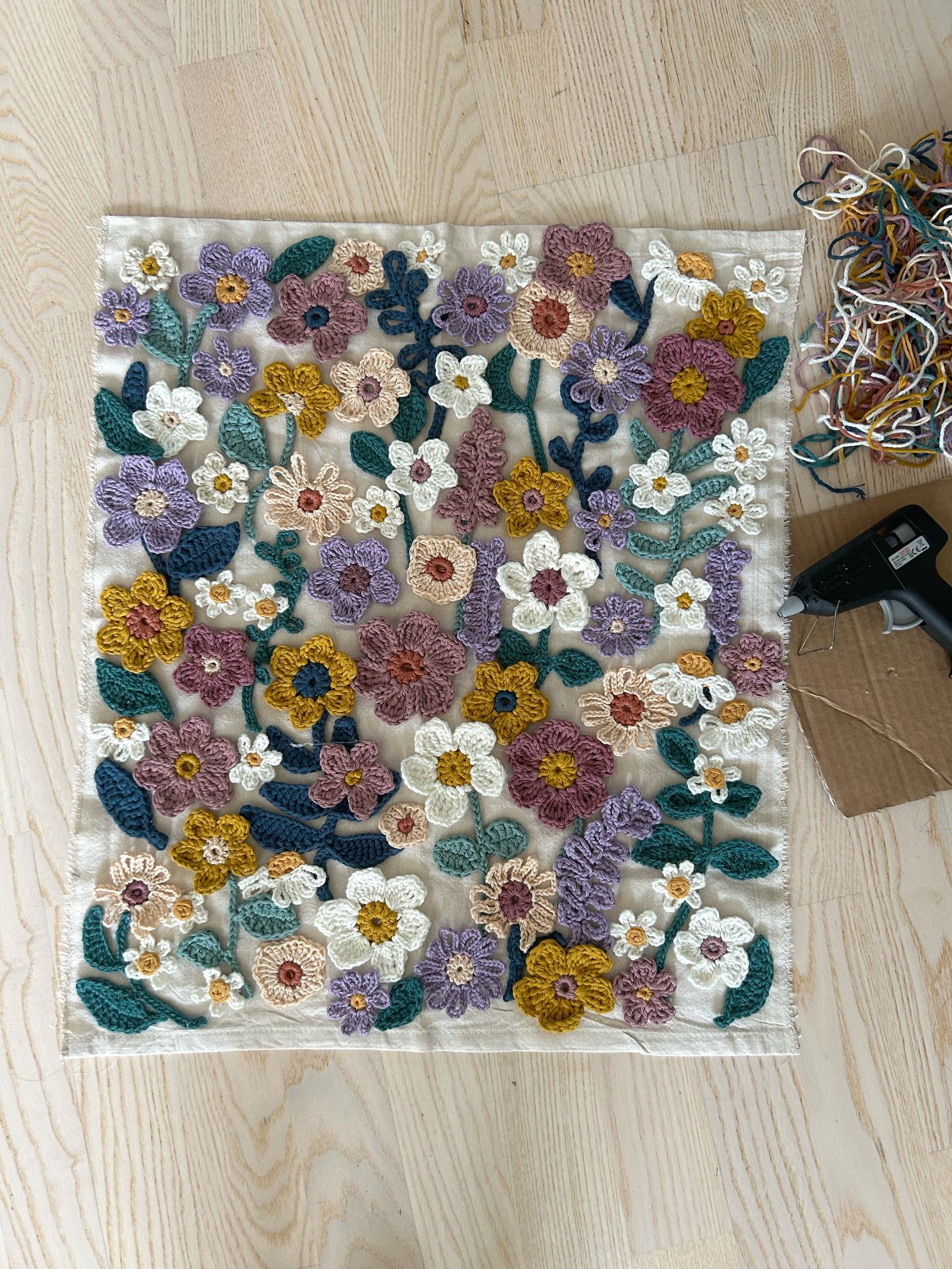 Crocheted flowers arranged on the surface of the canvas.