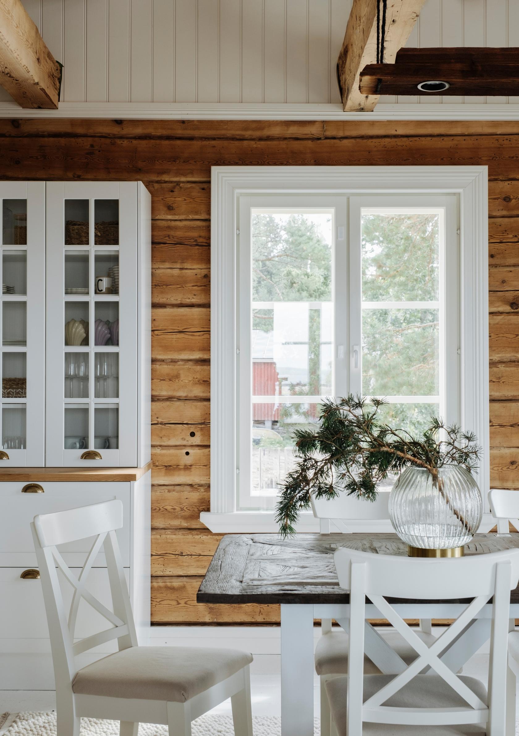 Country-style dining table and display cabinet in a log-walled living room