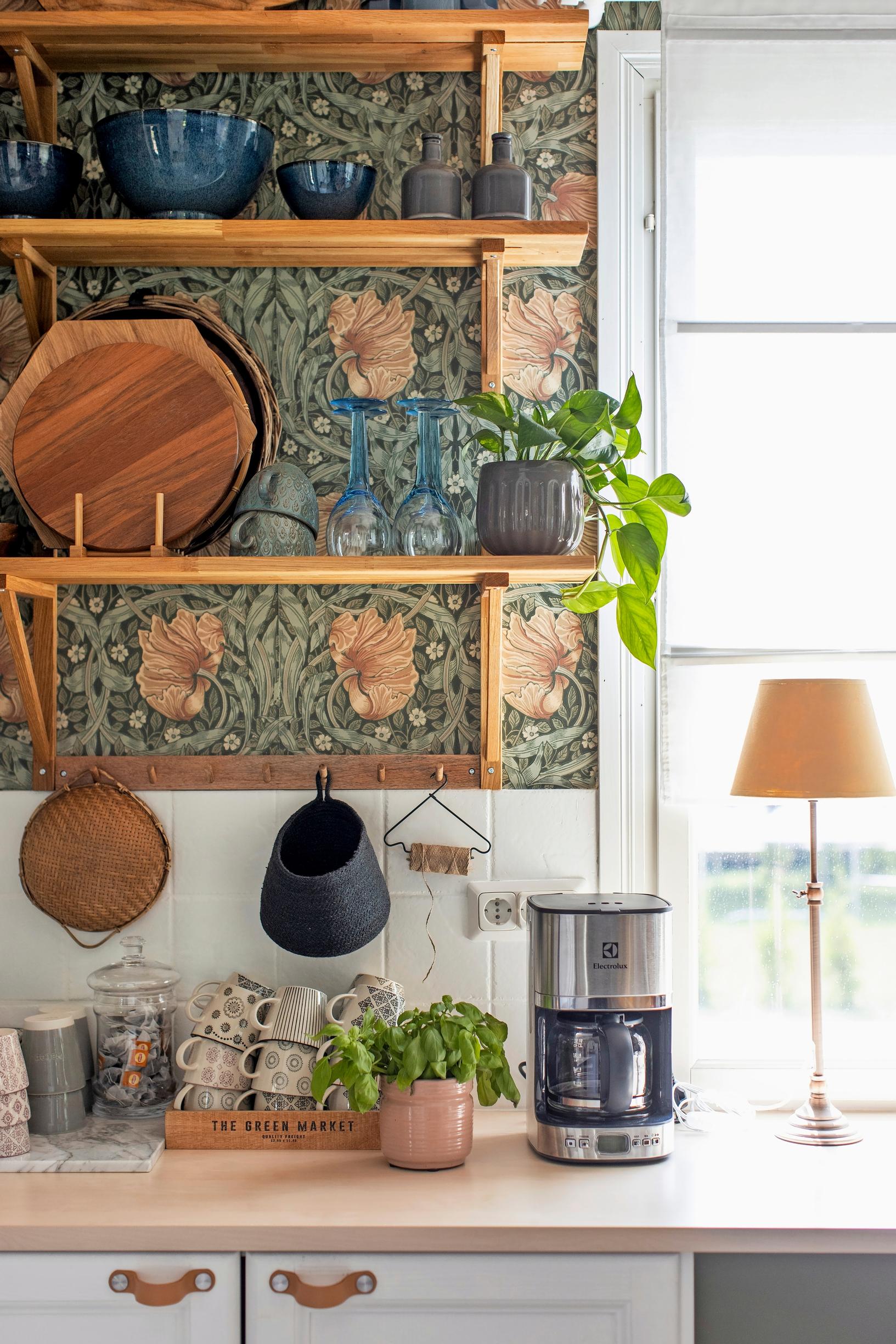 Attractive kitchen supplies on an open shelf, backed by wallpaper