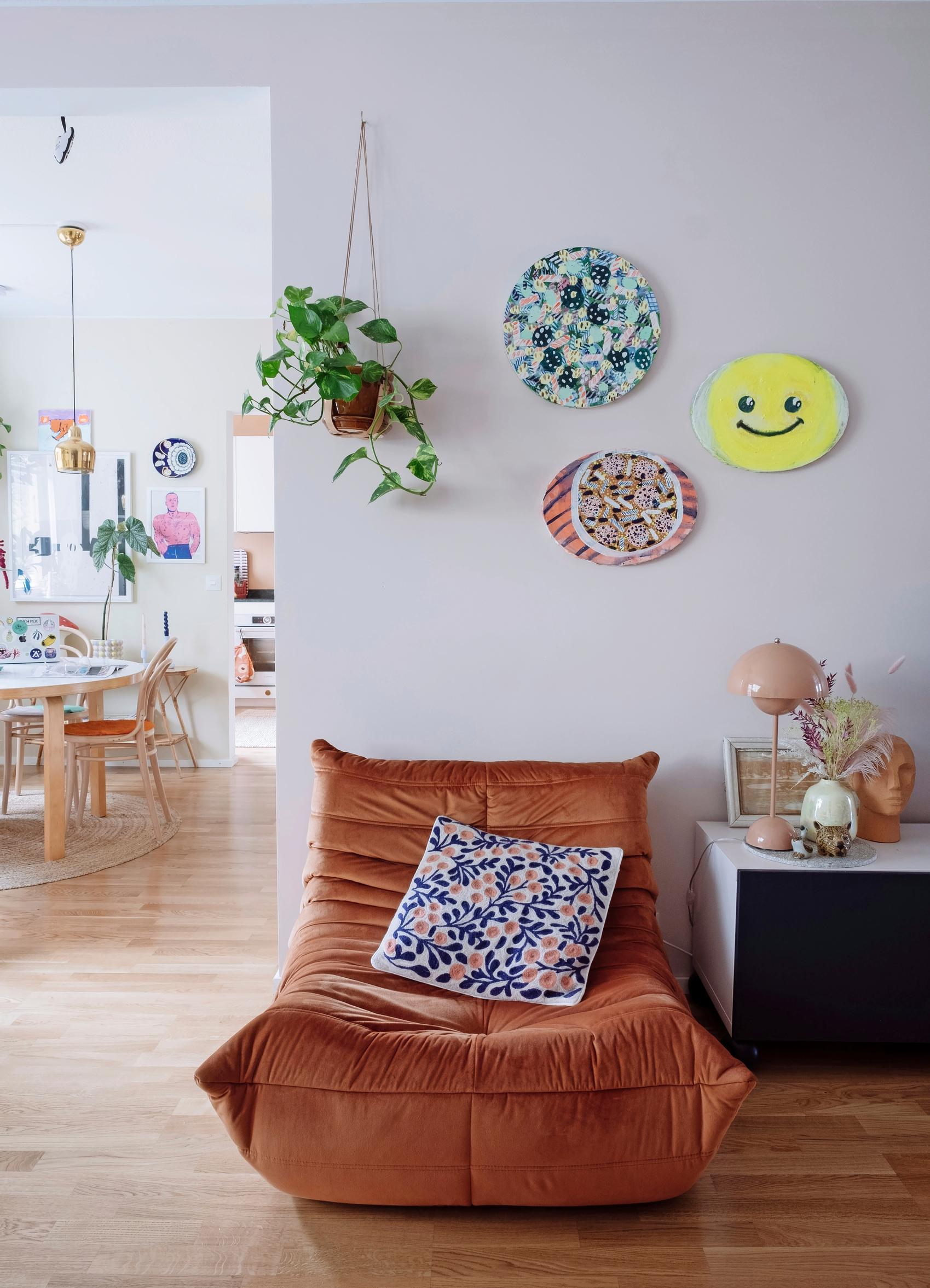 Vibrant artworks above the brick-colored lounge chair