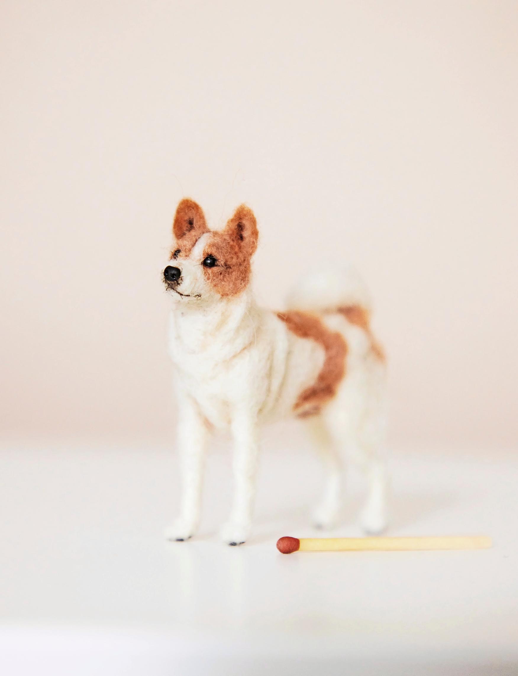 The photo shows a felted dog and a matchstick.