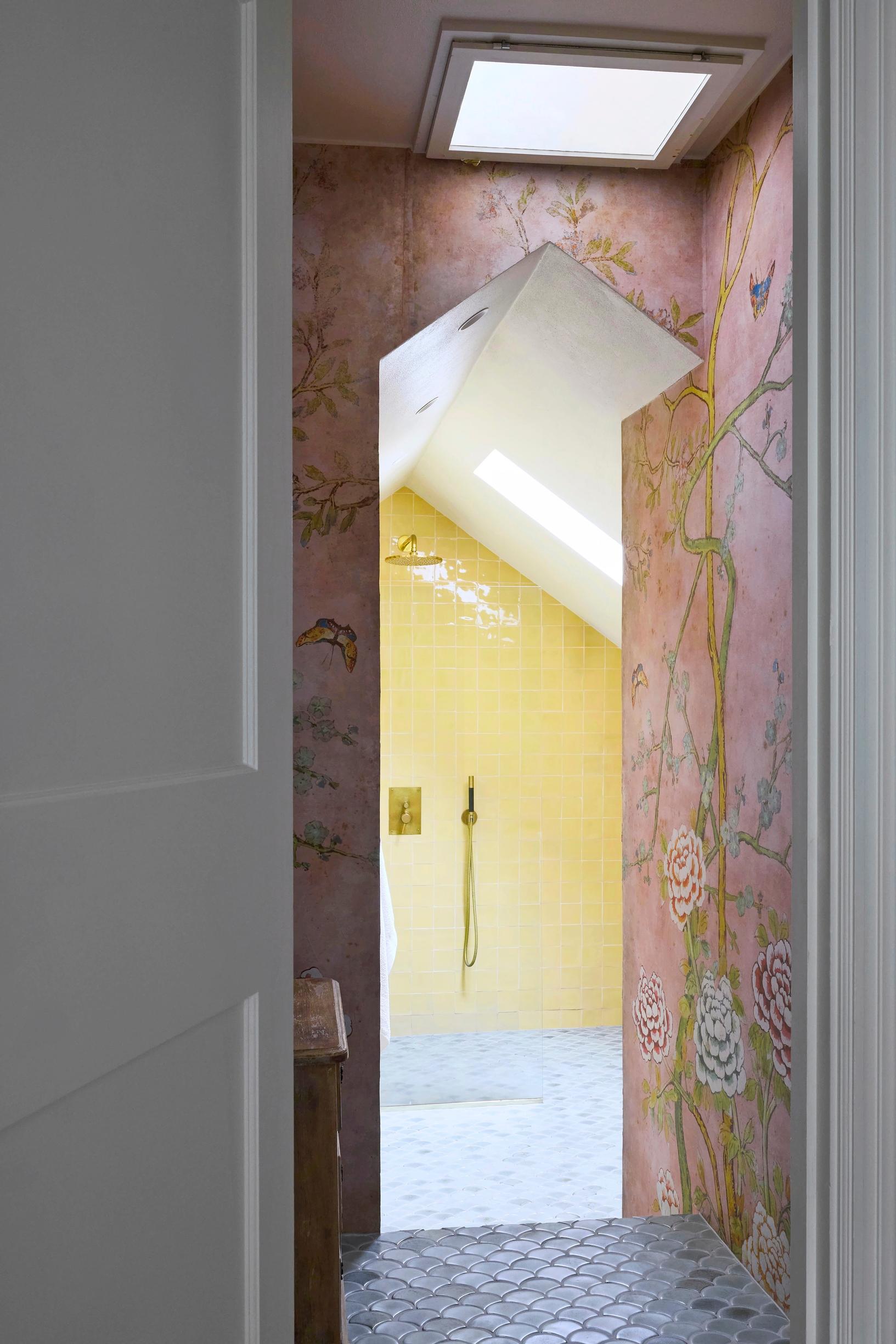 In the downstairs bathroom, there are yellow and blue tiles and pink wallpaper
