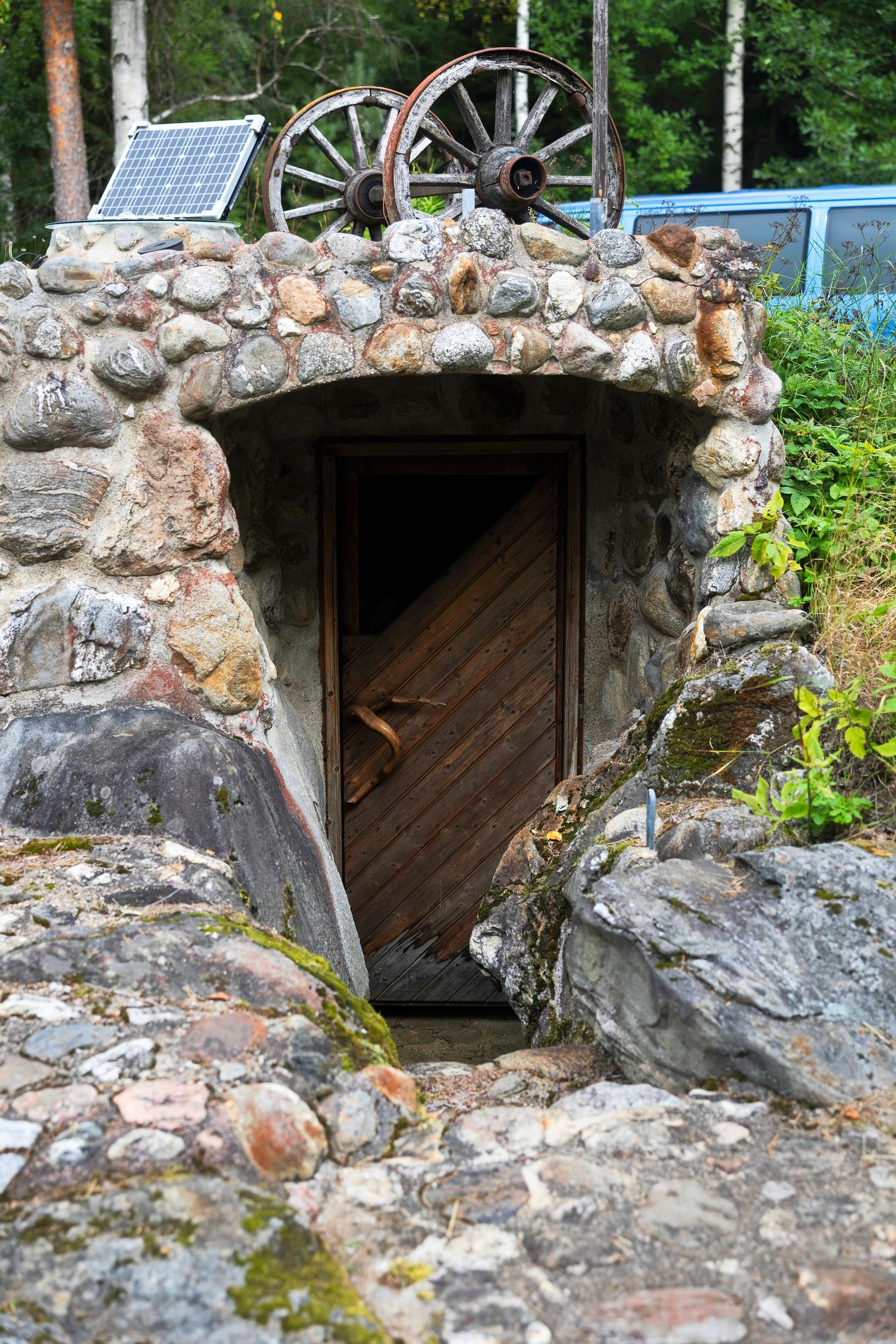 The door of a sauna built of natural stones, with wagon wheels on the roof