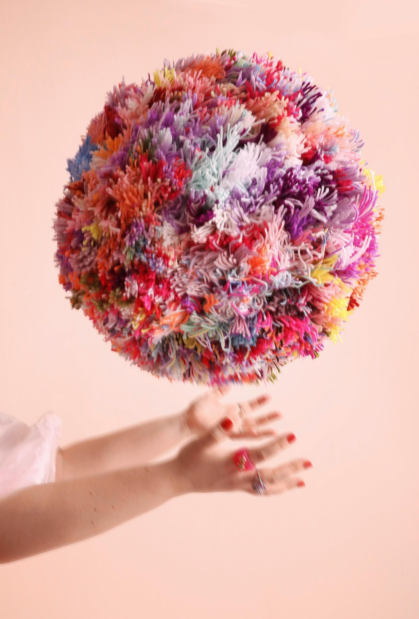 Mari holding a giant pom-pom.