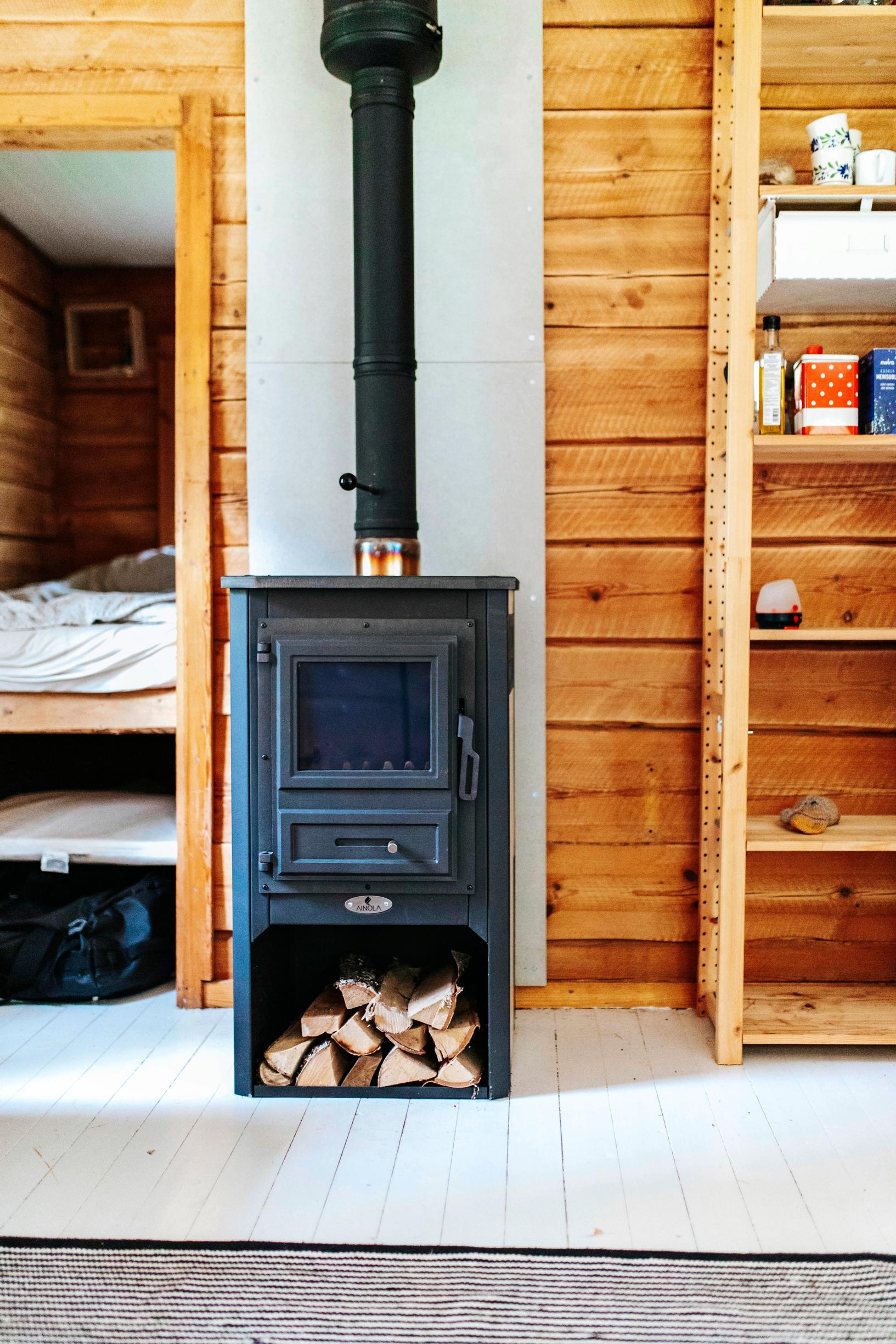 A wood-burning stove against a log wall in the cottage.