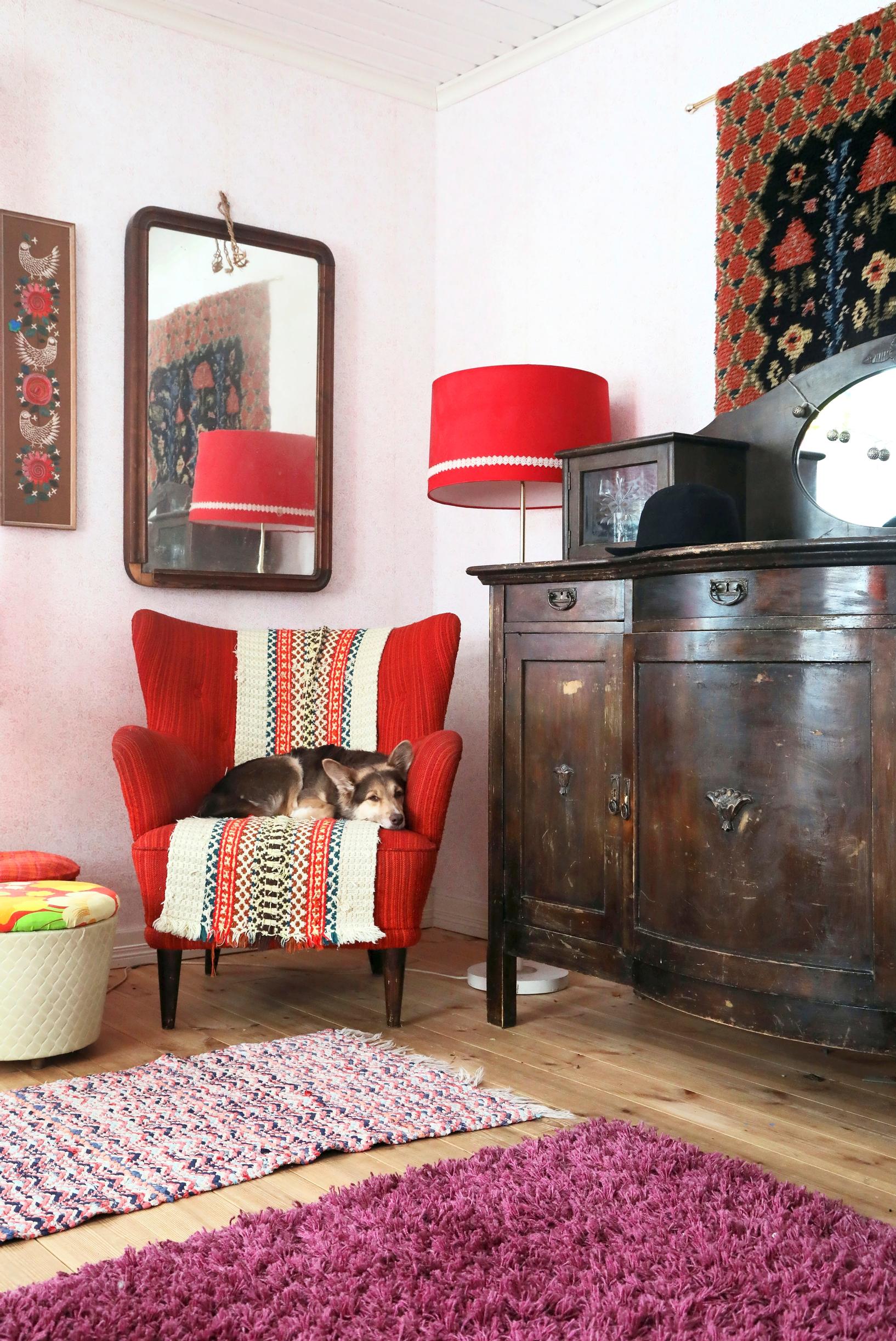 A red armchair and a dark antique dresser in the Rissa family’s living room.