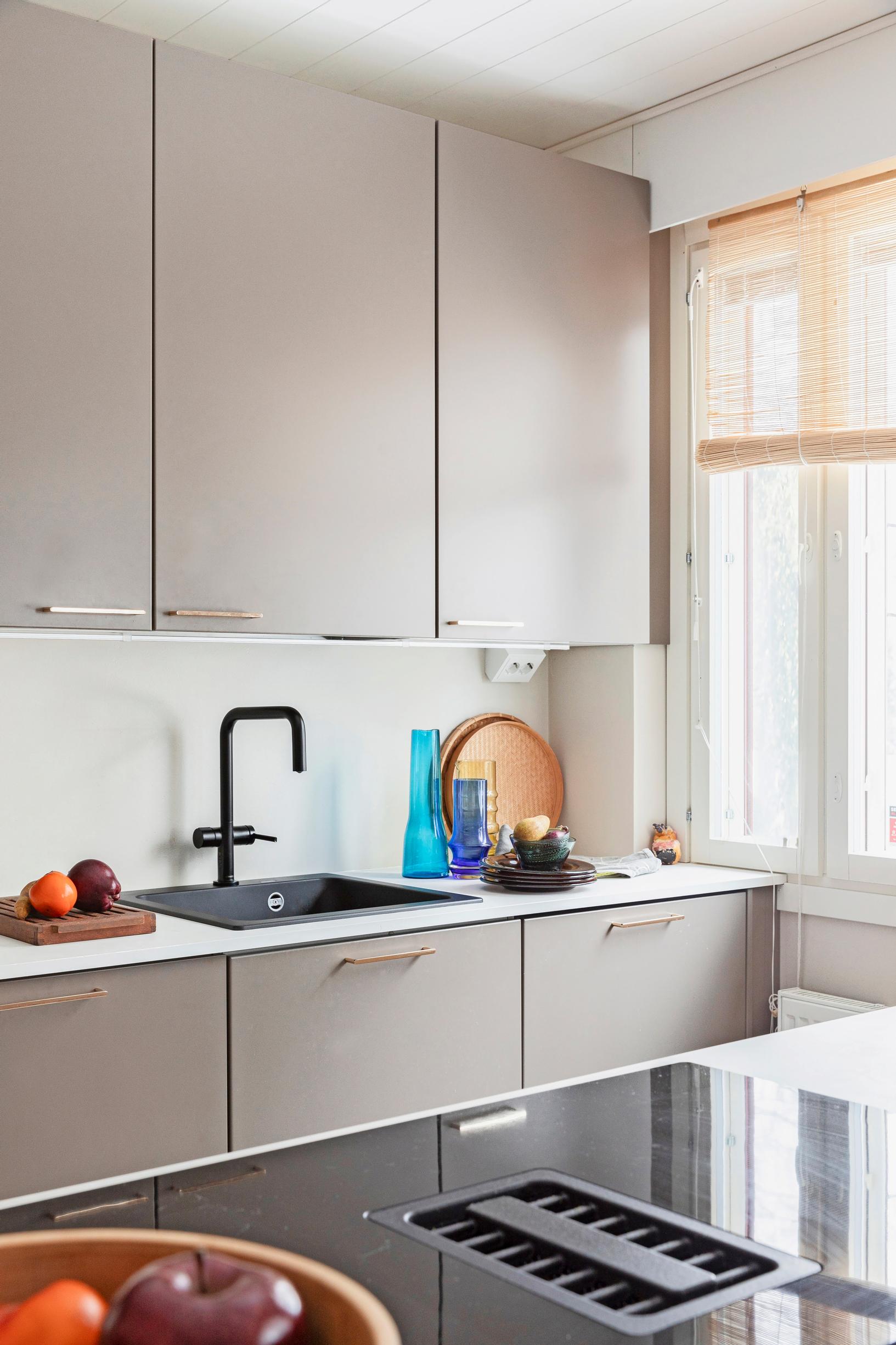 Photo of the open-plan kitchen with an island and grayish cabinets.