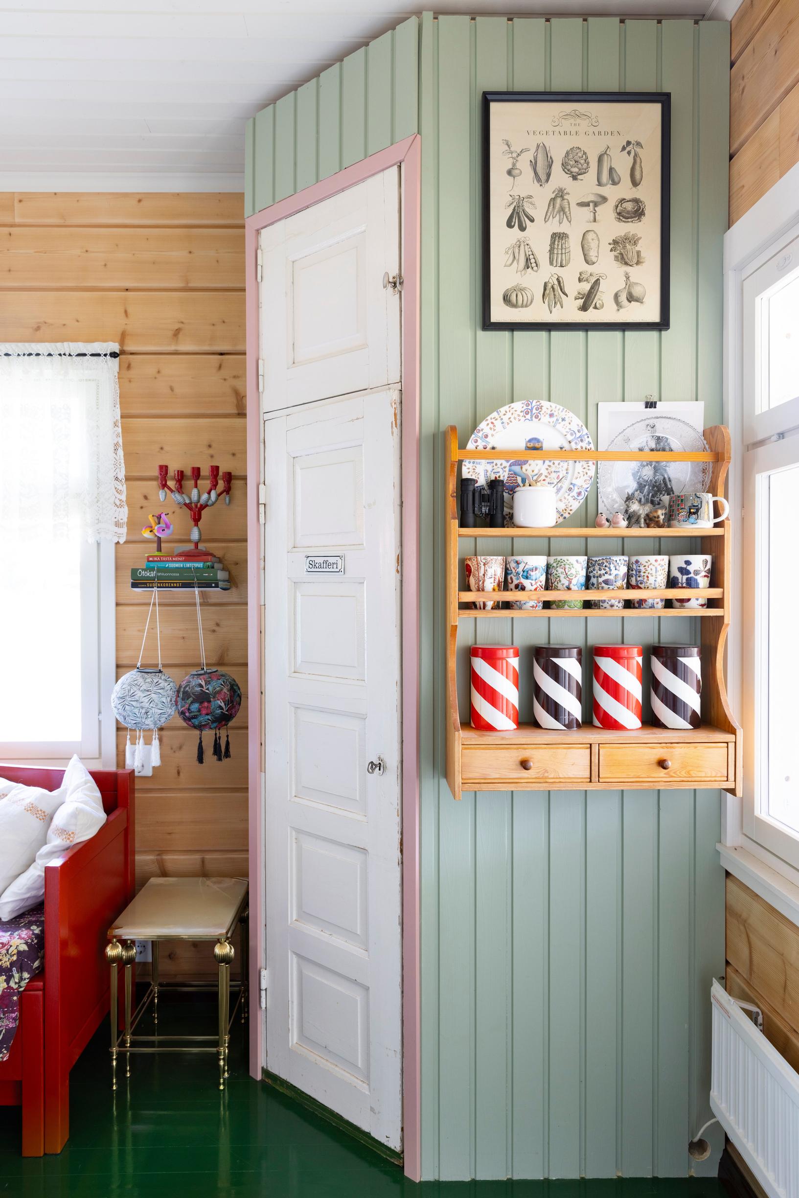 A corner cabinet and green wood-paneled walls