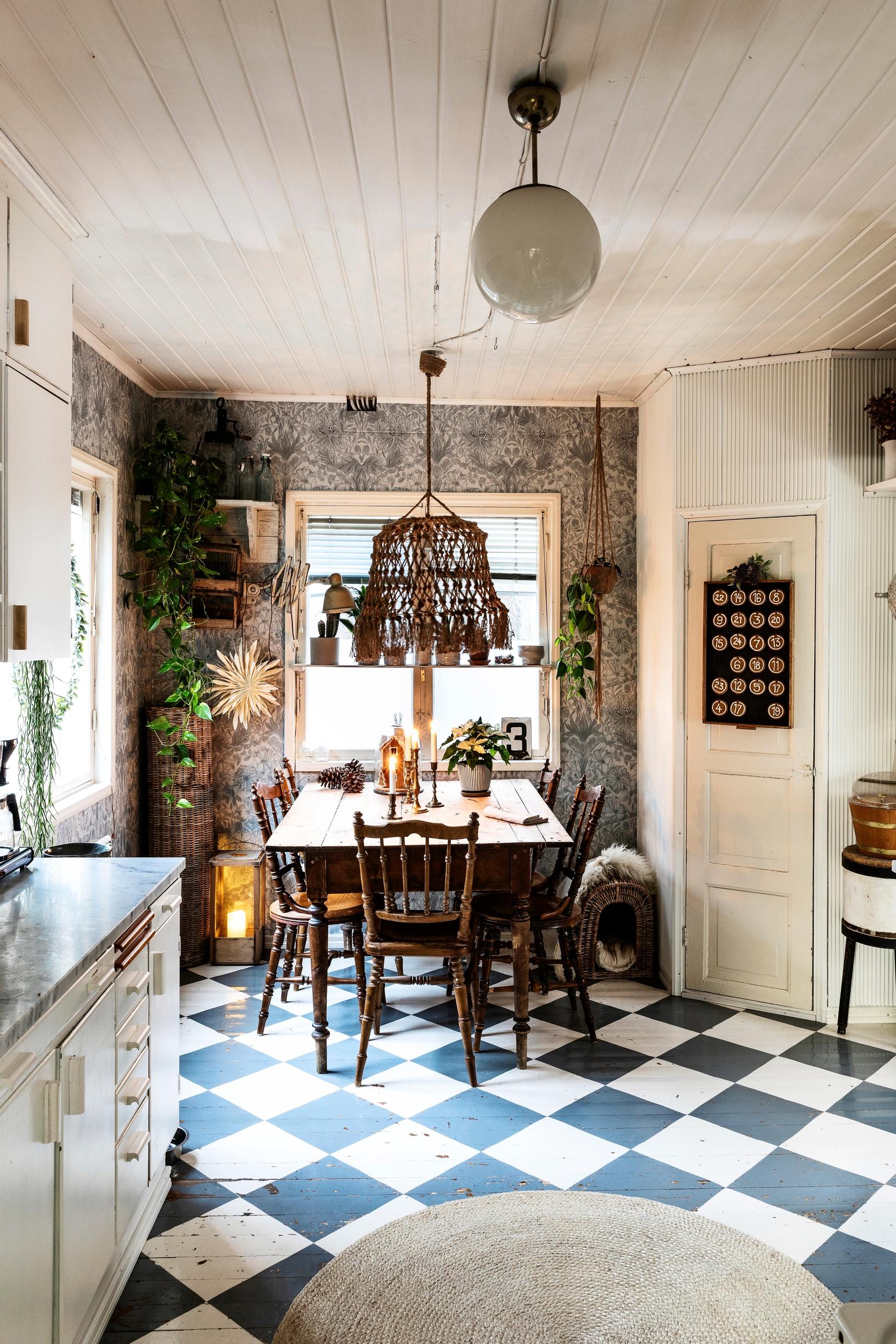 A kitchen with a black-and-white checkered floor and Morris & Co’s Pure Honeysuckle & Tulip wallpaper