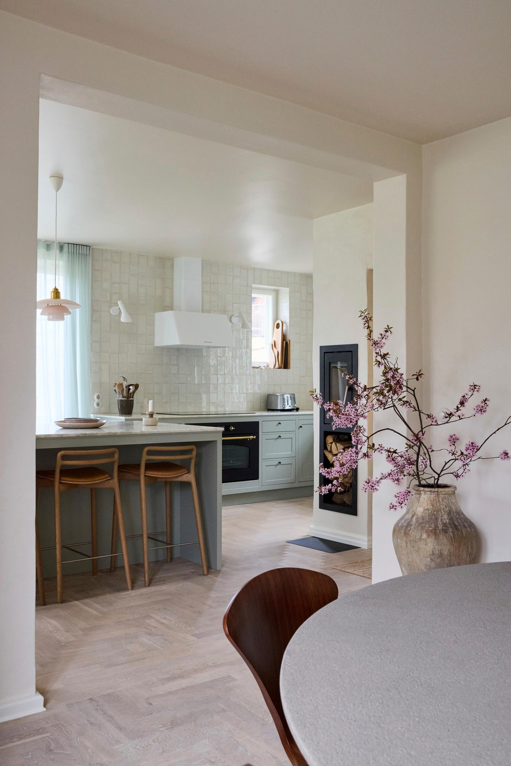 A mint-green solid-wood kitchen with an island and bar stools