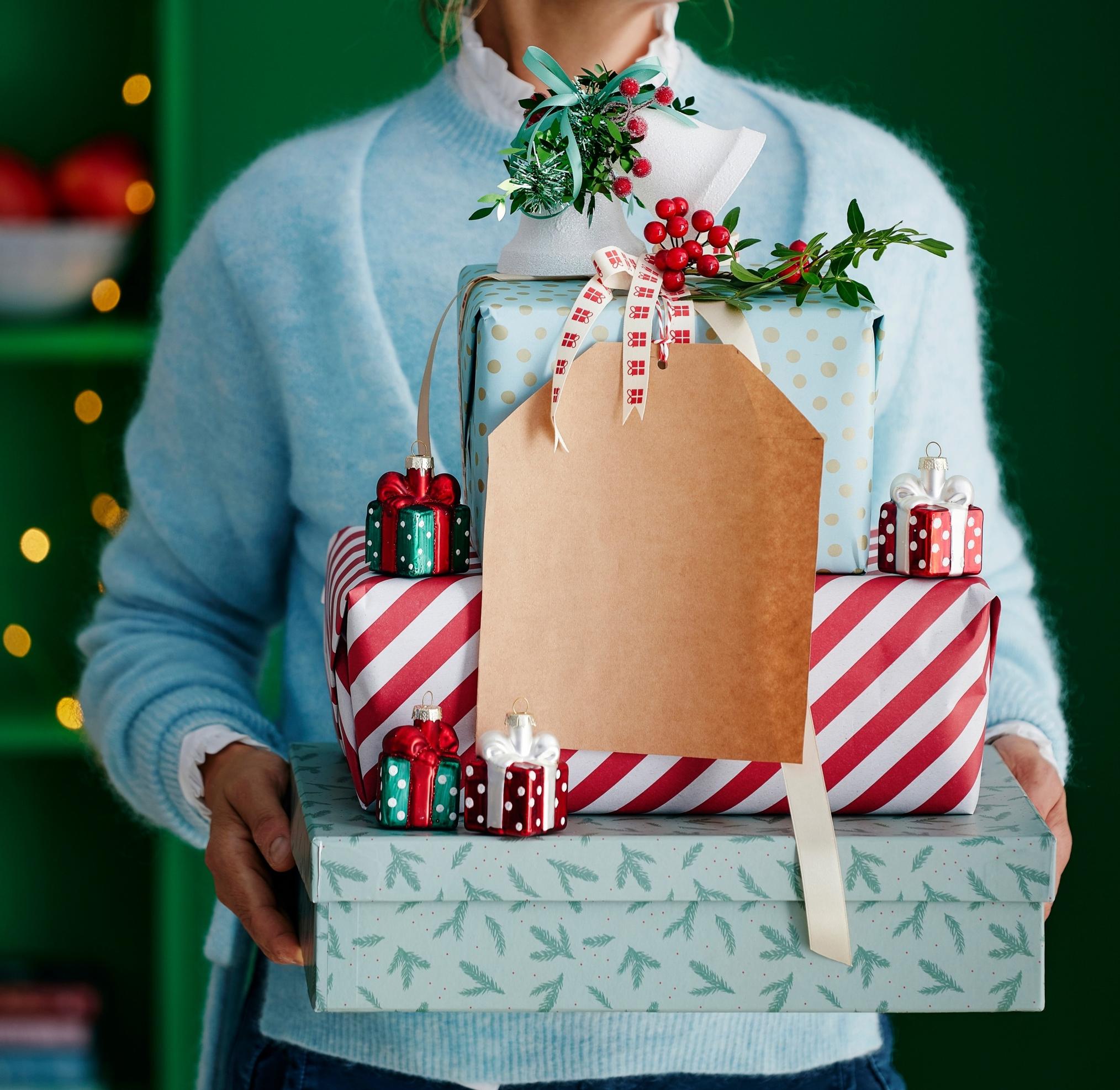 A woman is carrying a stack of packages.