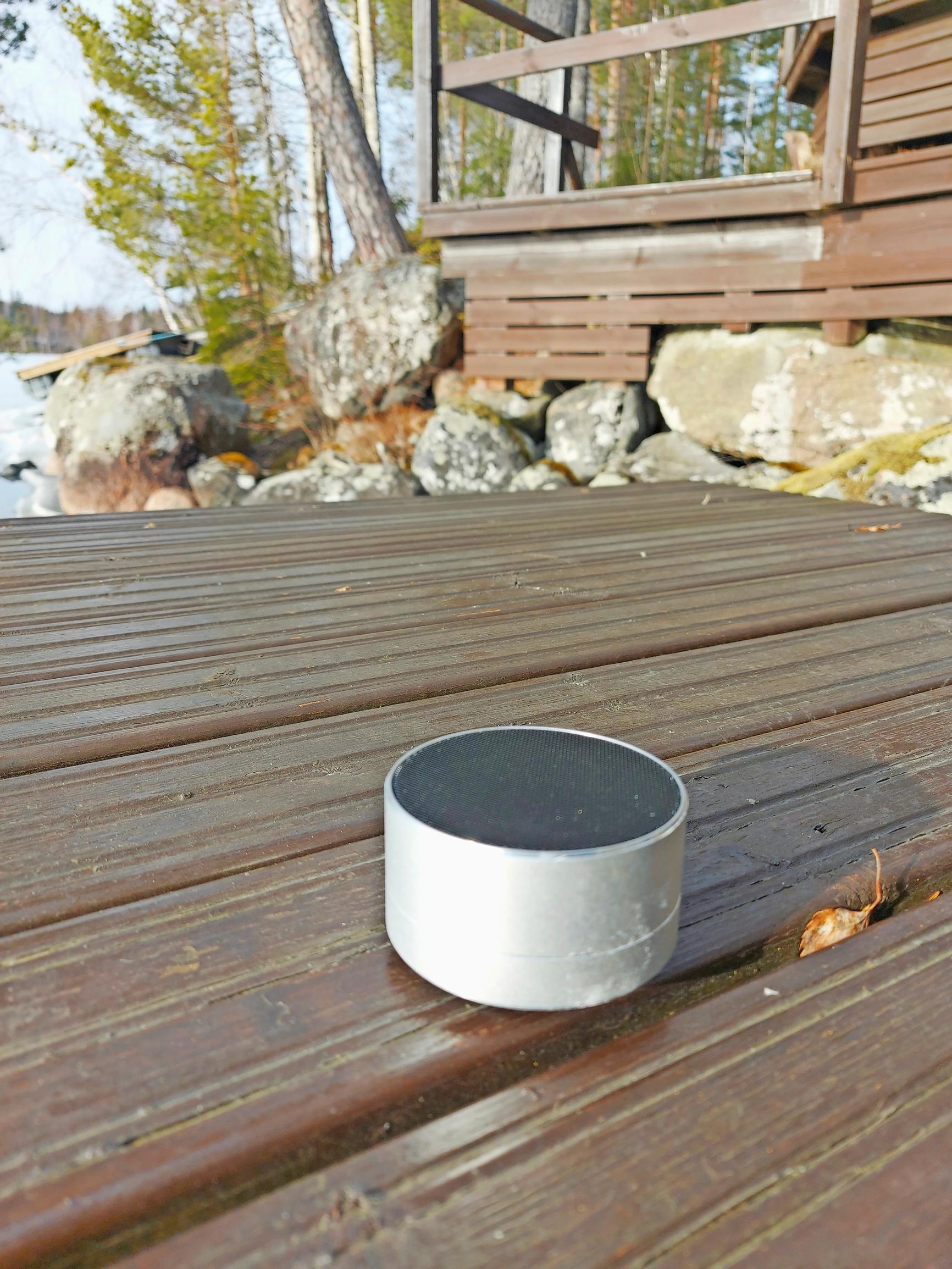 A small round device (the sound beacon) on the patio in front of the cabin