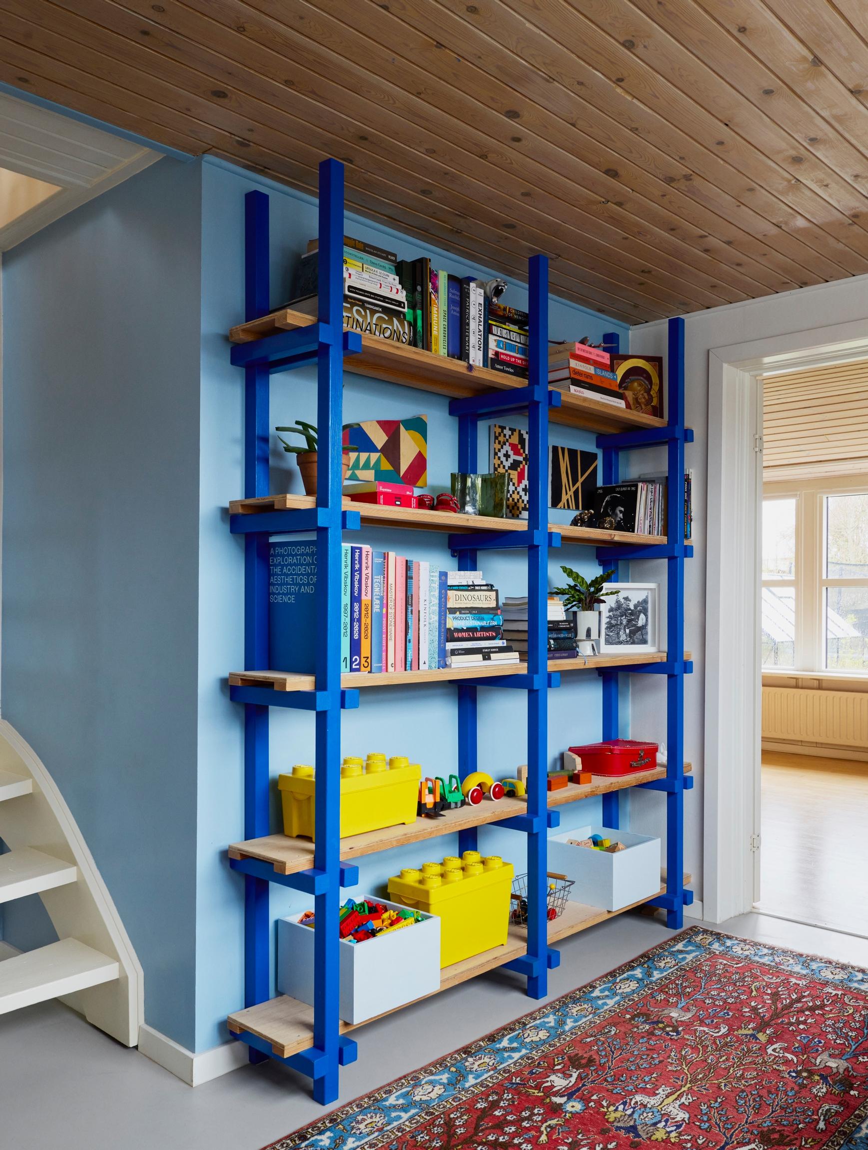 In the downstairs hallway, a combined library and playroom with a blue bookshelf.