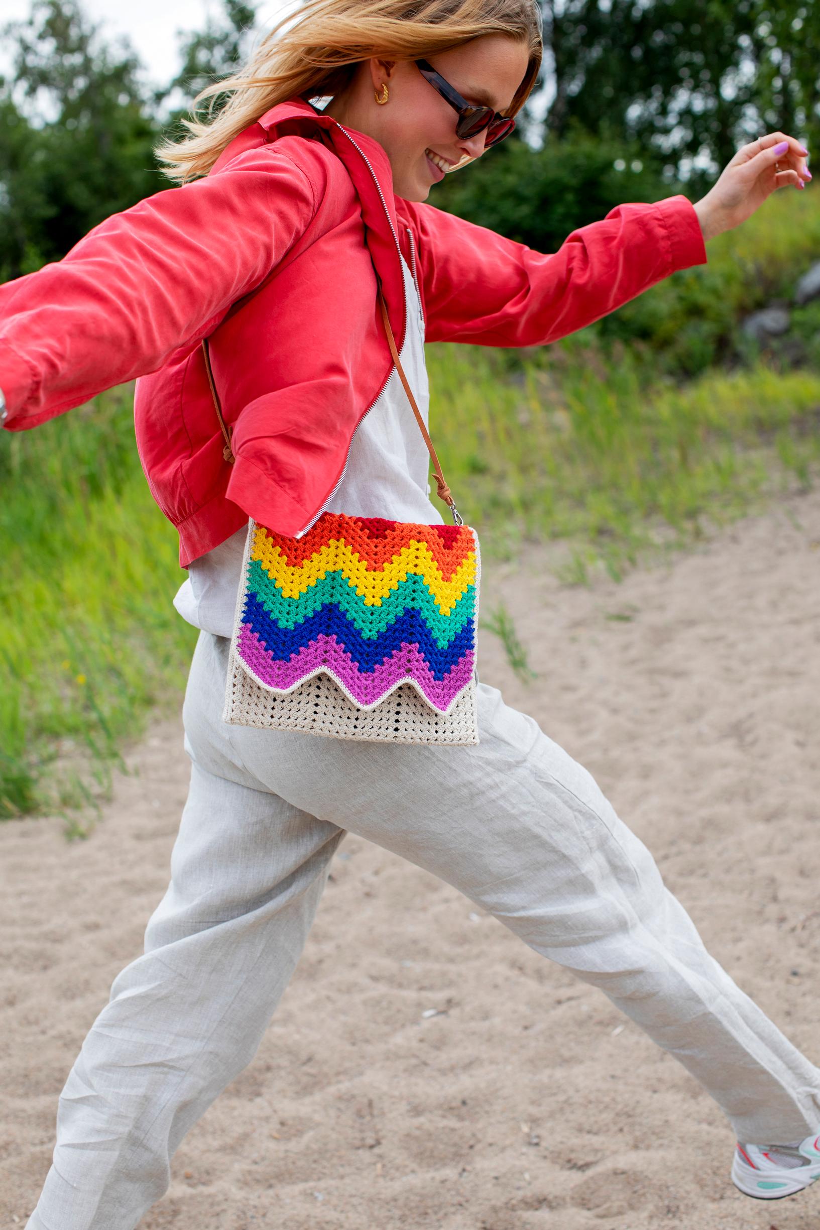 Crocheted rainbow bag on model’s shoulder
