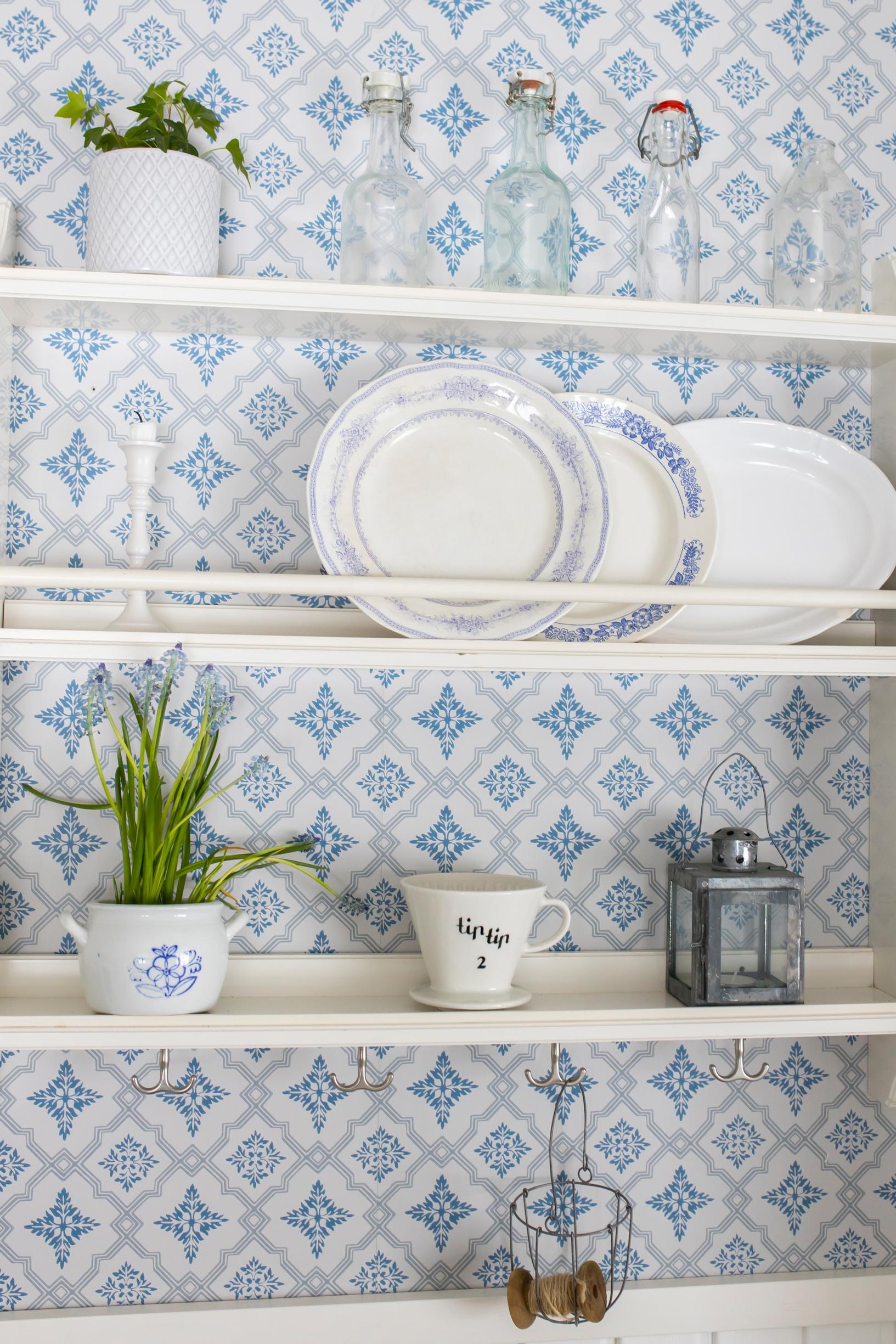 Blue patterned wallpaper behind the dish shelf